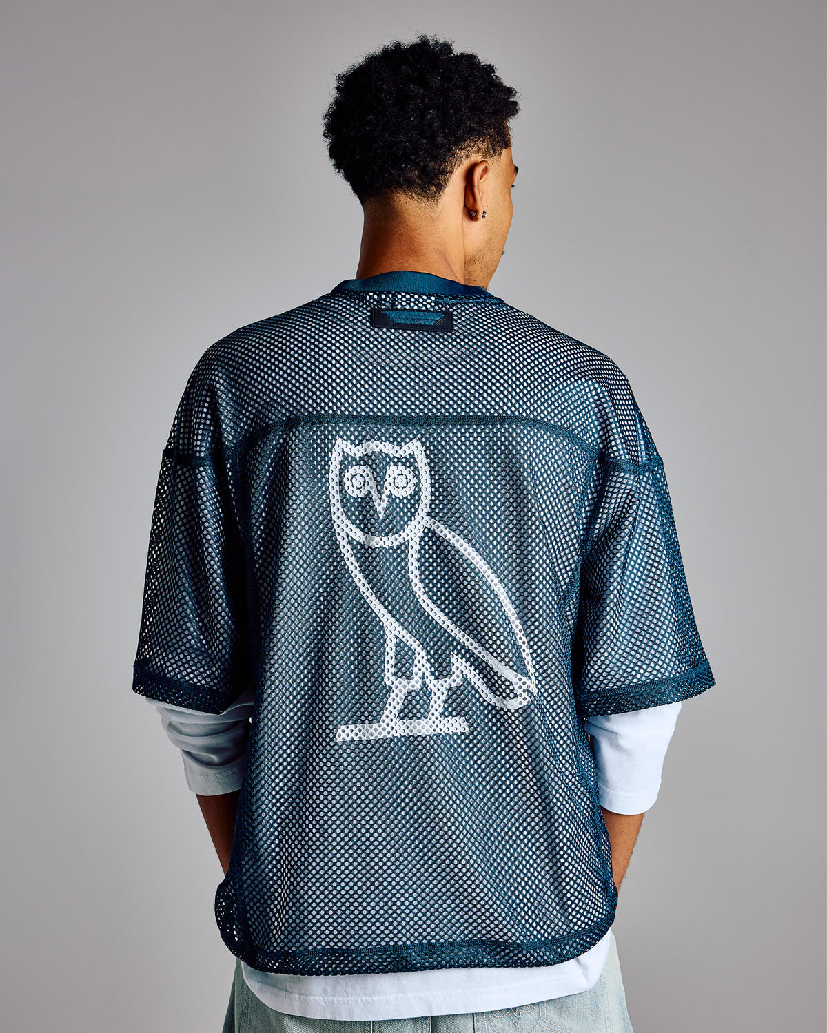Dark blue mesh football jersey with white owl graphic on back, worn over white long-sleeve shirt.