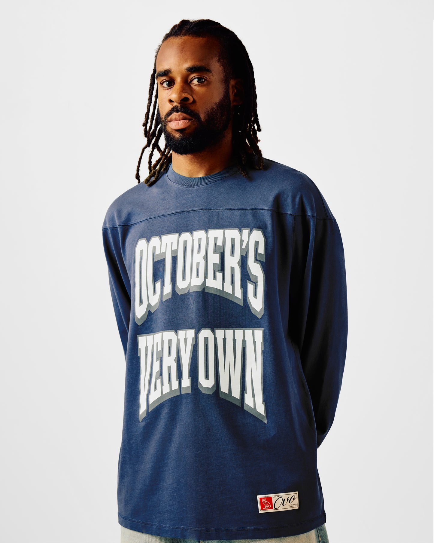 Navy long-sleeve football tee with white "October's Very Own" text and small logo patch on lower left.
