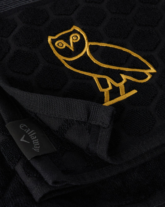 Black golf towel with gold embroidered Callaway owl logo and ribbed trim.