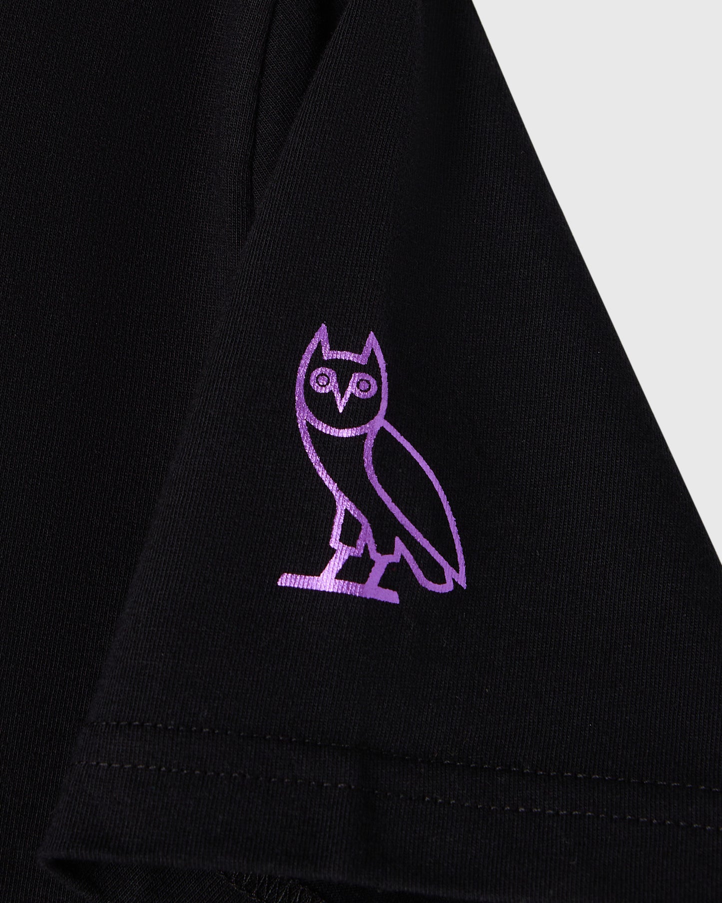 Black t-shirt with purple embroidered owl graphic on chest.