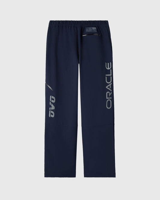 Navy nylon pants with reflective "ORACLE" text down the legs and drawstring waist.
