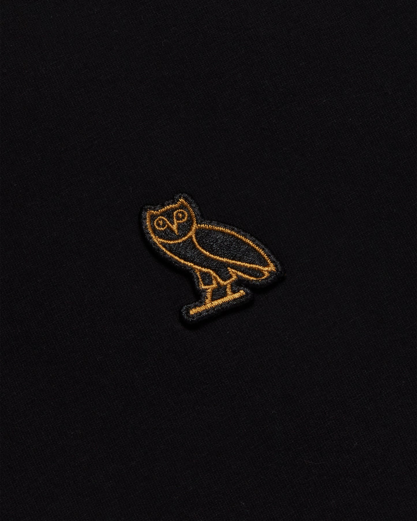 Black long-sleeve tee with gold embroidered owl design on chest.