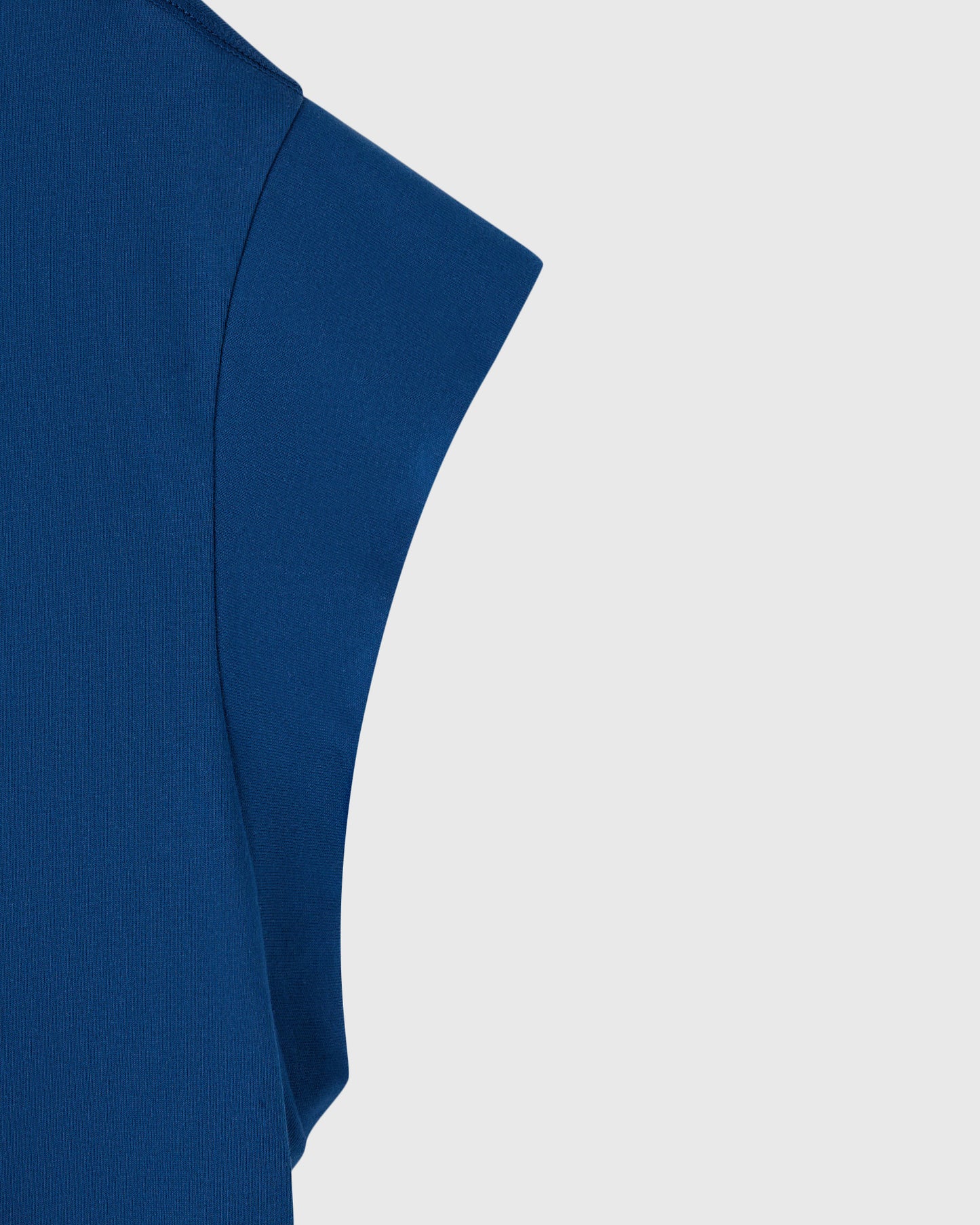 Deep denim blue sleeveless muscle tee with mesh texture and curved seaming detail.