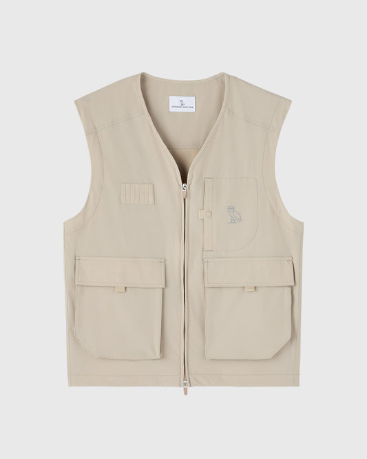 Sandstone nylon vest with front zip, multiple pockets, and small owl embroidery on chest.