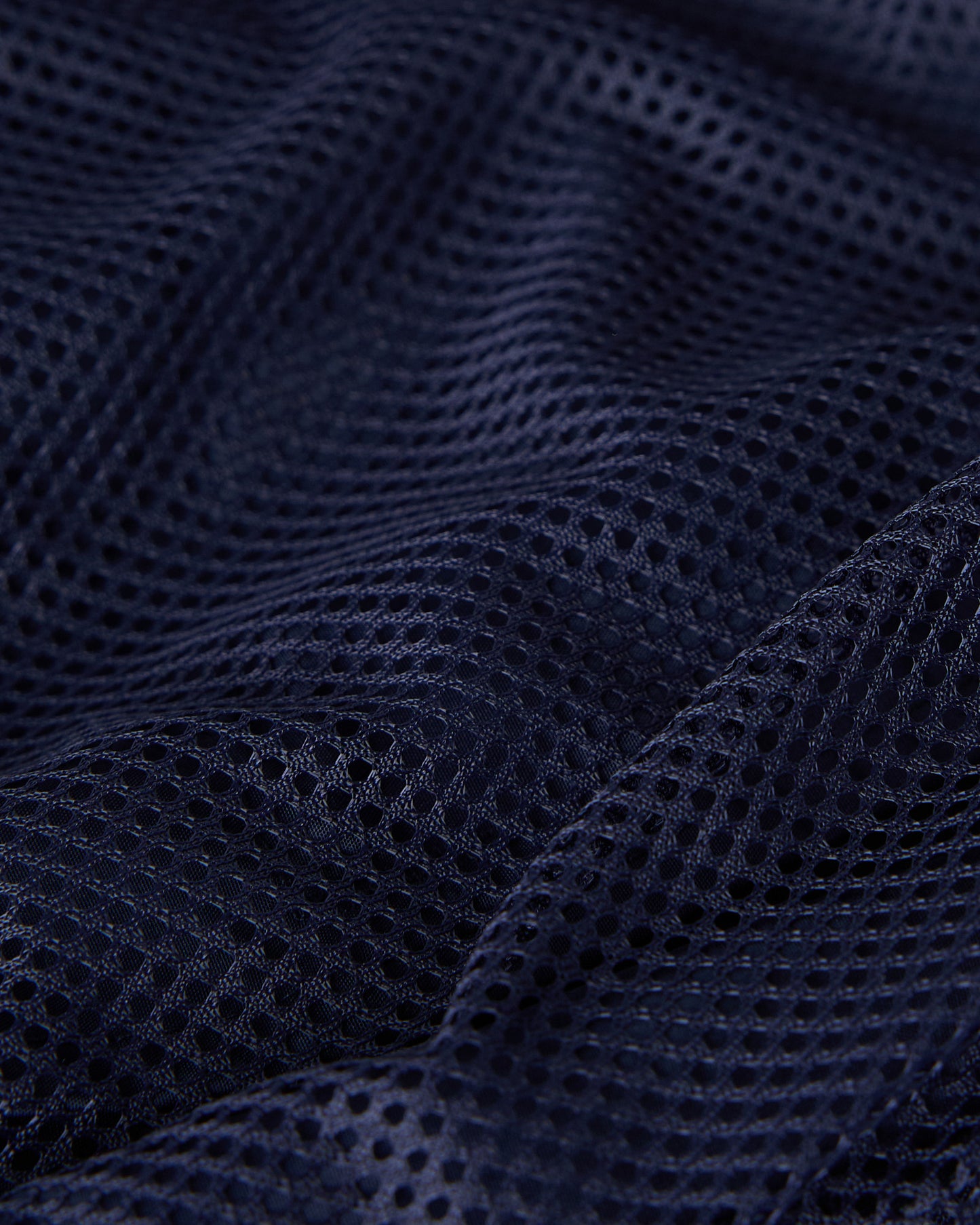Navy mesh swim short fabric showing textured weave pattern and draping.