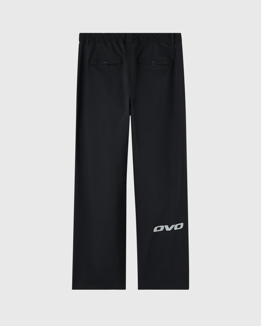 Black stretch nylon chino pants with elastic waistband, rear patch pockets, and OVO logo on leg.