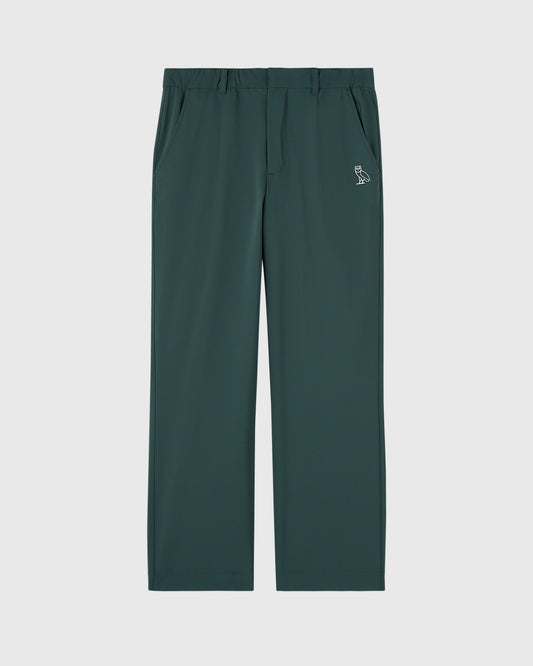 Midnight green chino pants with flat front, side pockets, and small owl logo on thigh.