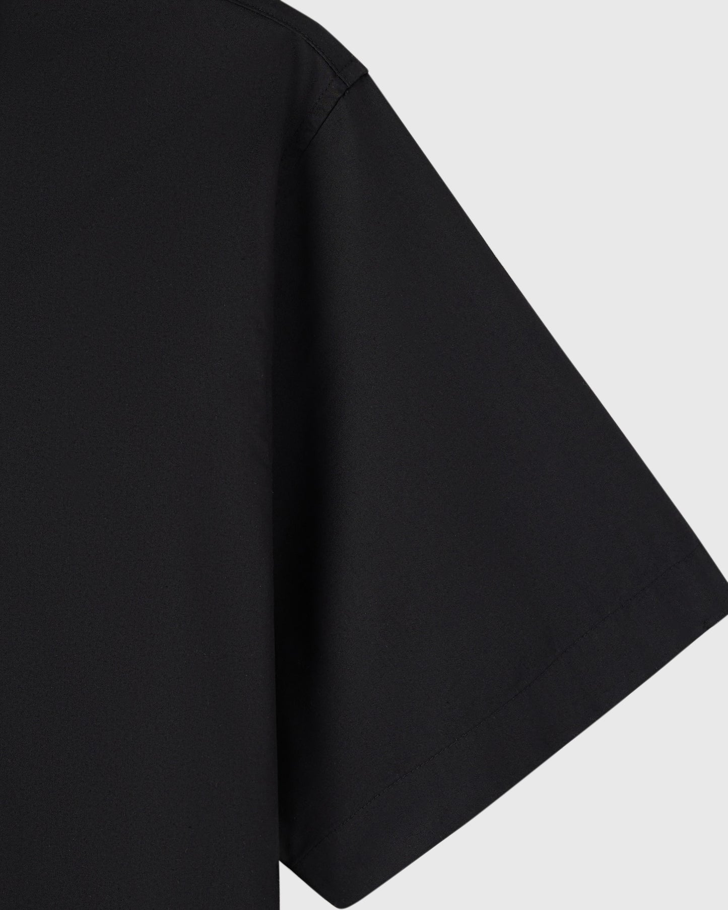 Black camp shirt with short sleeves and relaxed fit displayed against white background.