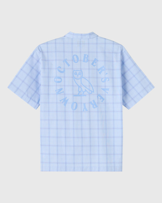 Light blue camp shirt with grid pattern and circular wordmark design on back.