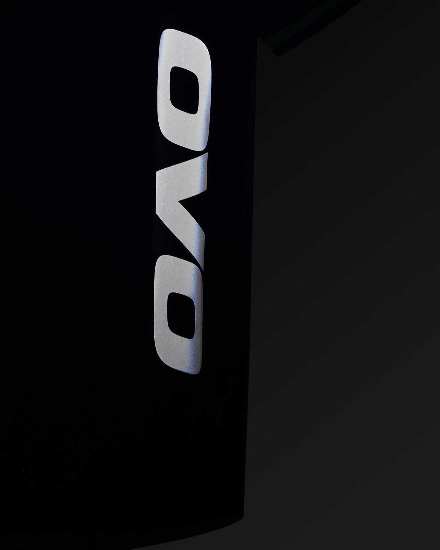 White OVO logo vertically aligned on deep denim blue polo shirt.