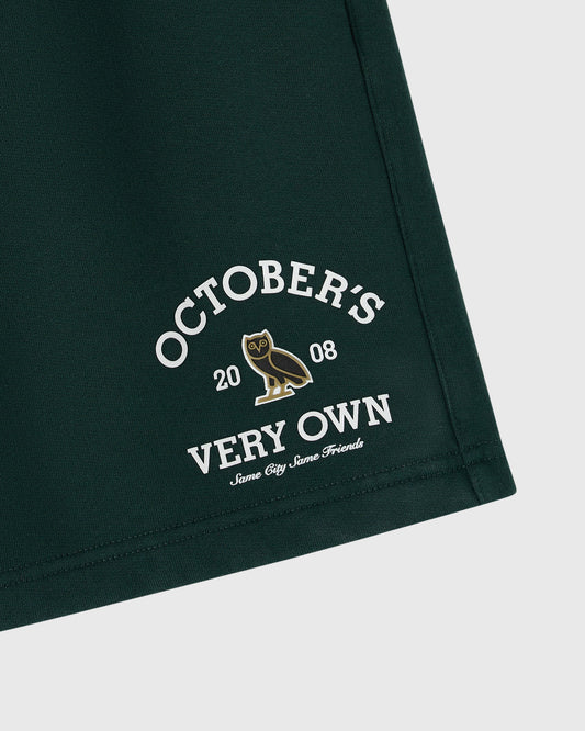 Midnight green shorts with white text reading "October's Very Own" and a gold owl graphic with "2008" printed on the leg.