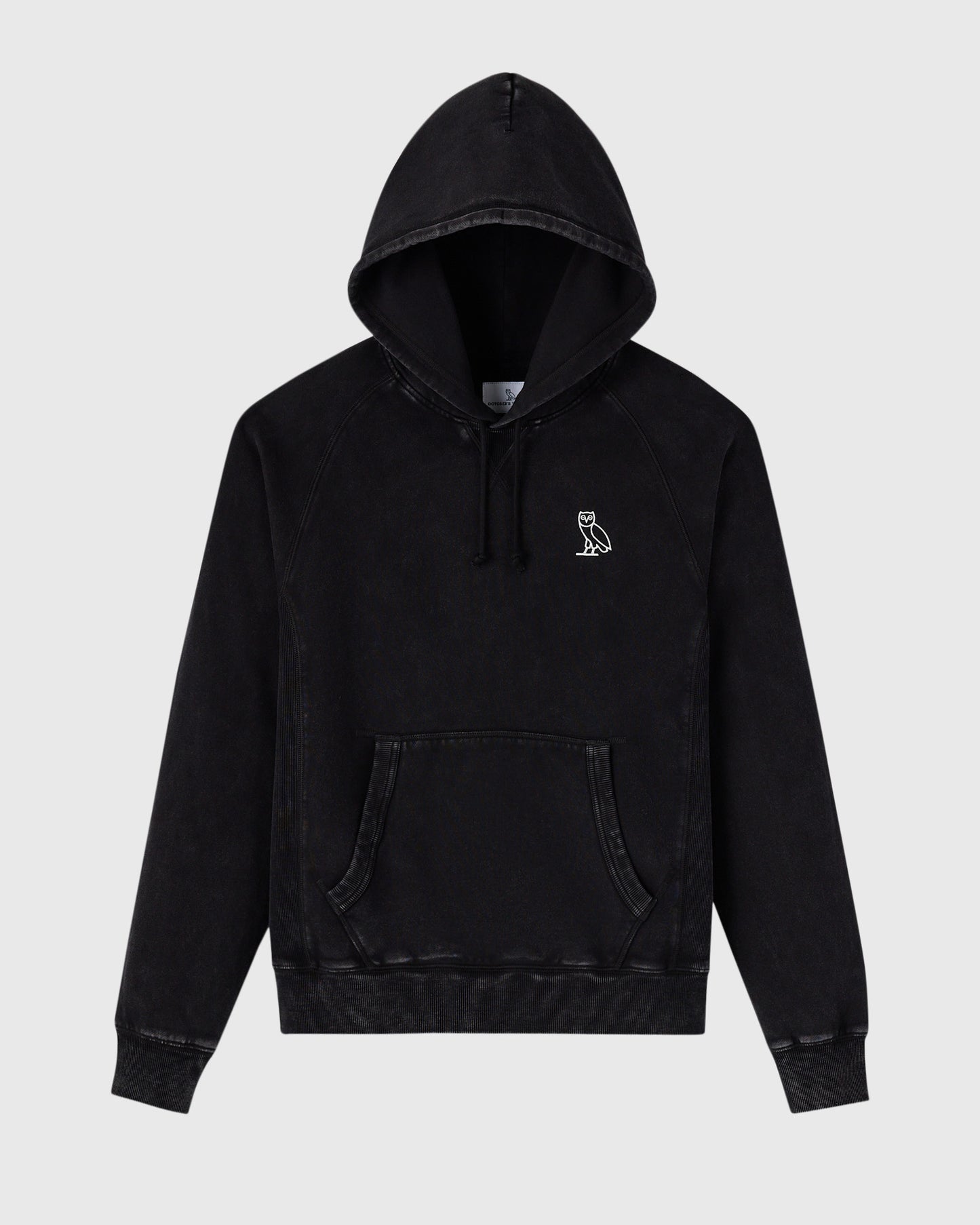 Black raglan hoodie with garment-dyed finish, drawstring hood, kangaroo pocket, and small owl embroidery on chest.