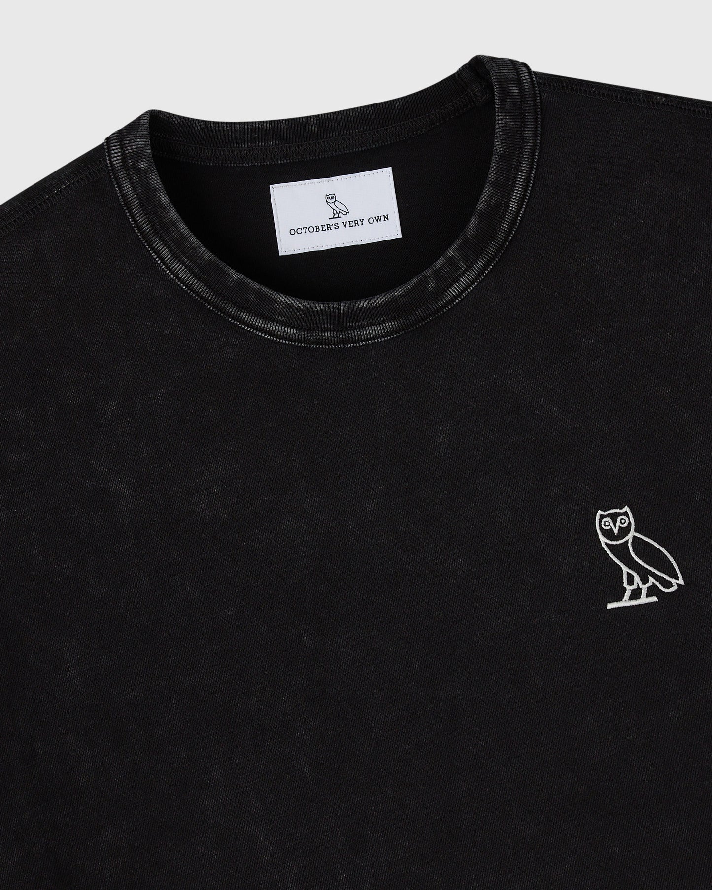 Black crewneck t-shirt with white owl embroidery on chest and brand label visible at neckline.