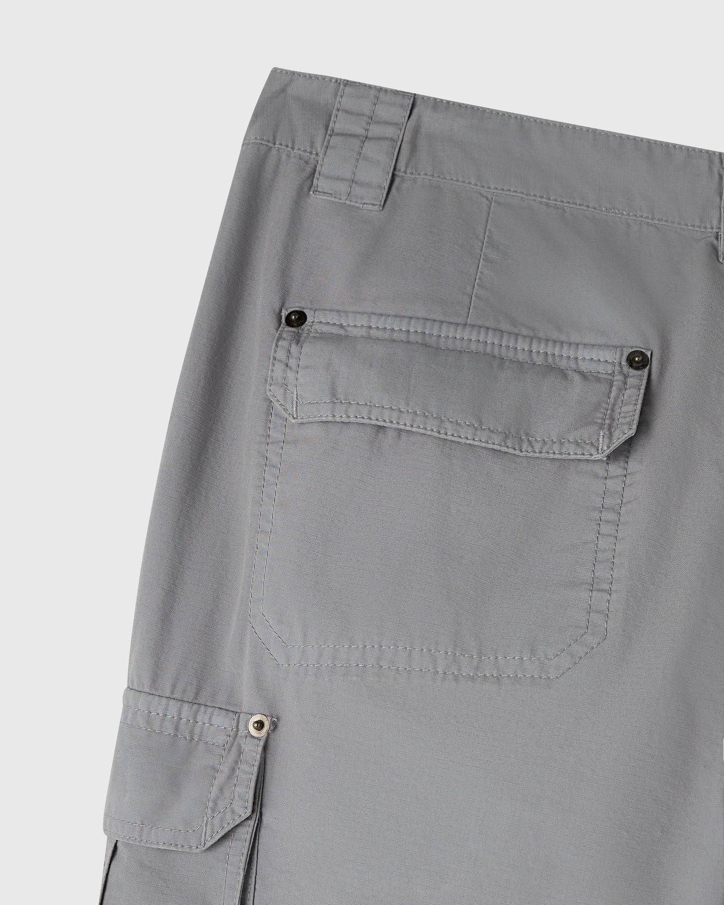 Grey cargo pants with multiple button-flap pockets on thigh and hip areas.