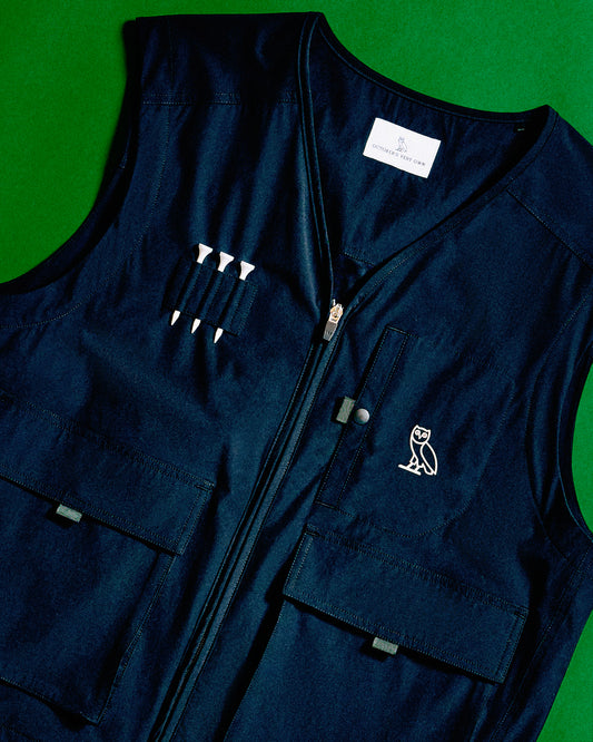 Dark blue stretch nylon vest with front zip closure, multiple pockets, and small owl logo on chest.