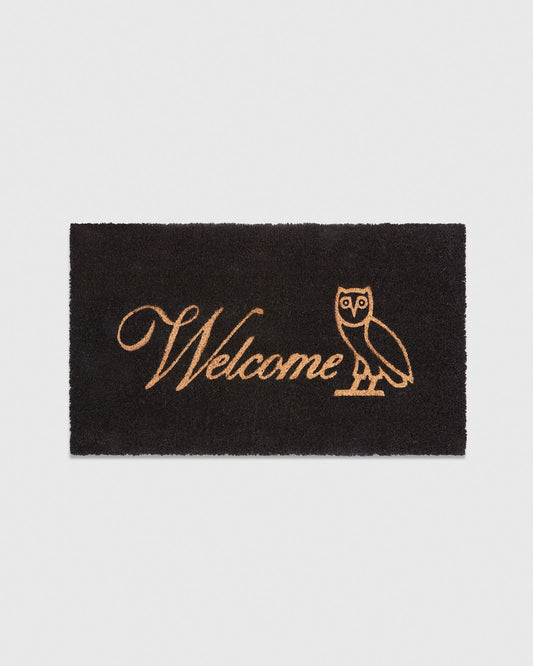 Black rectangular mat with tan "Welcome" text and owl illustration.
