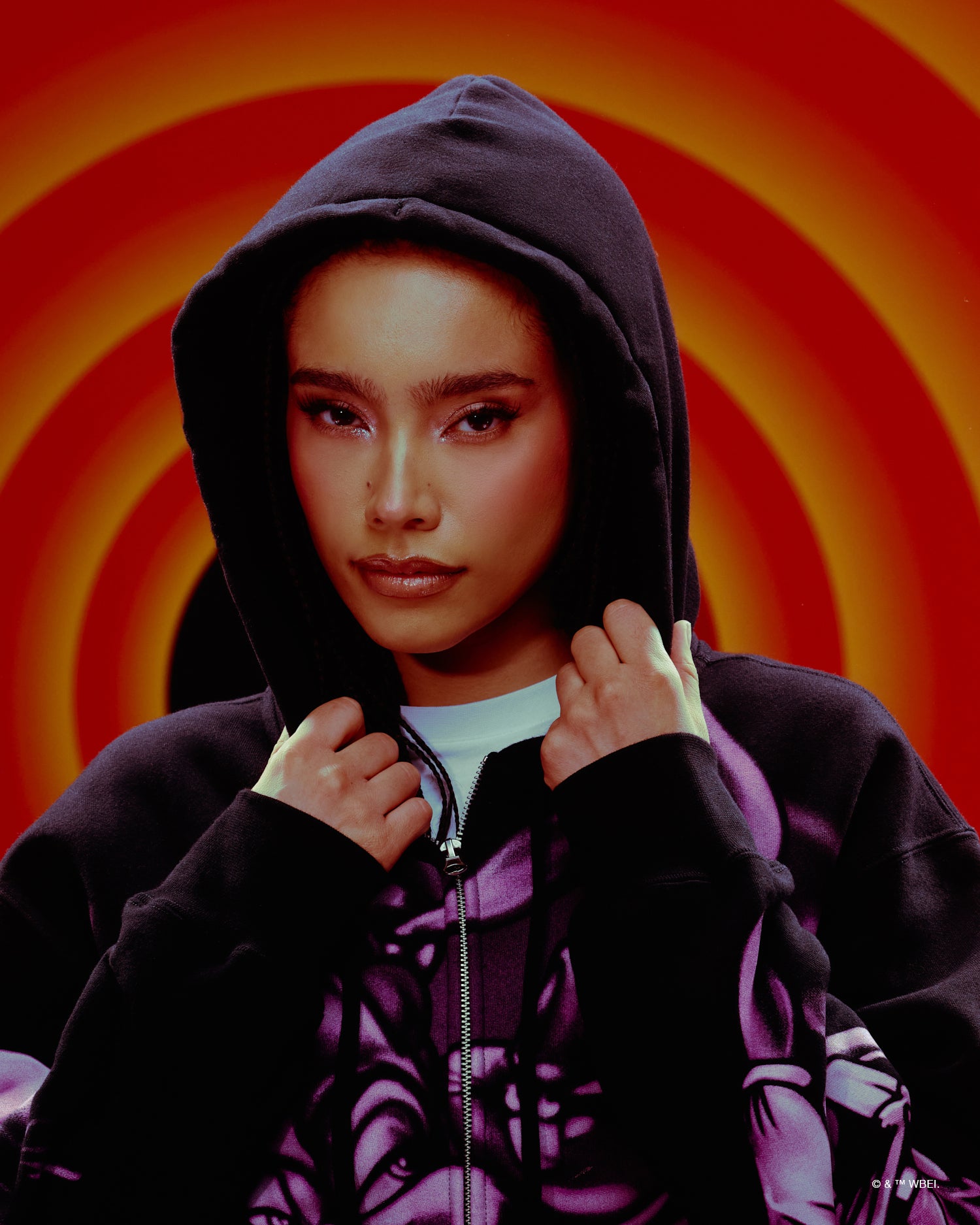 Person wearing a dark October's Very Own hoodie with a colourful circular background