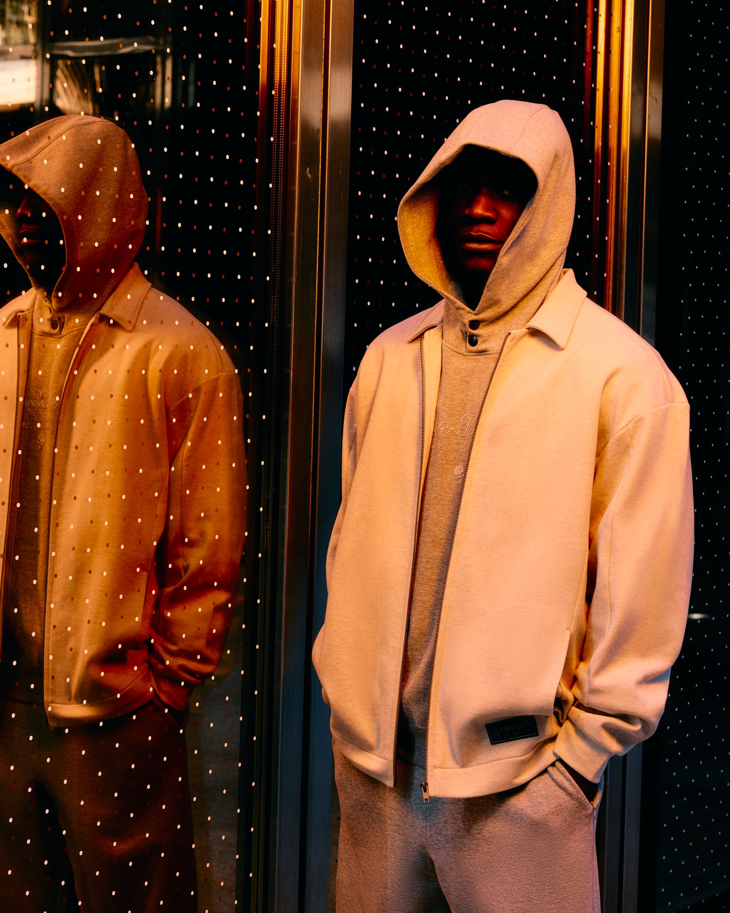 Person wearing a grey October's Very Own hoodie in front of a mirror with a starry background