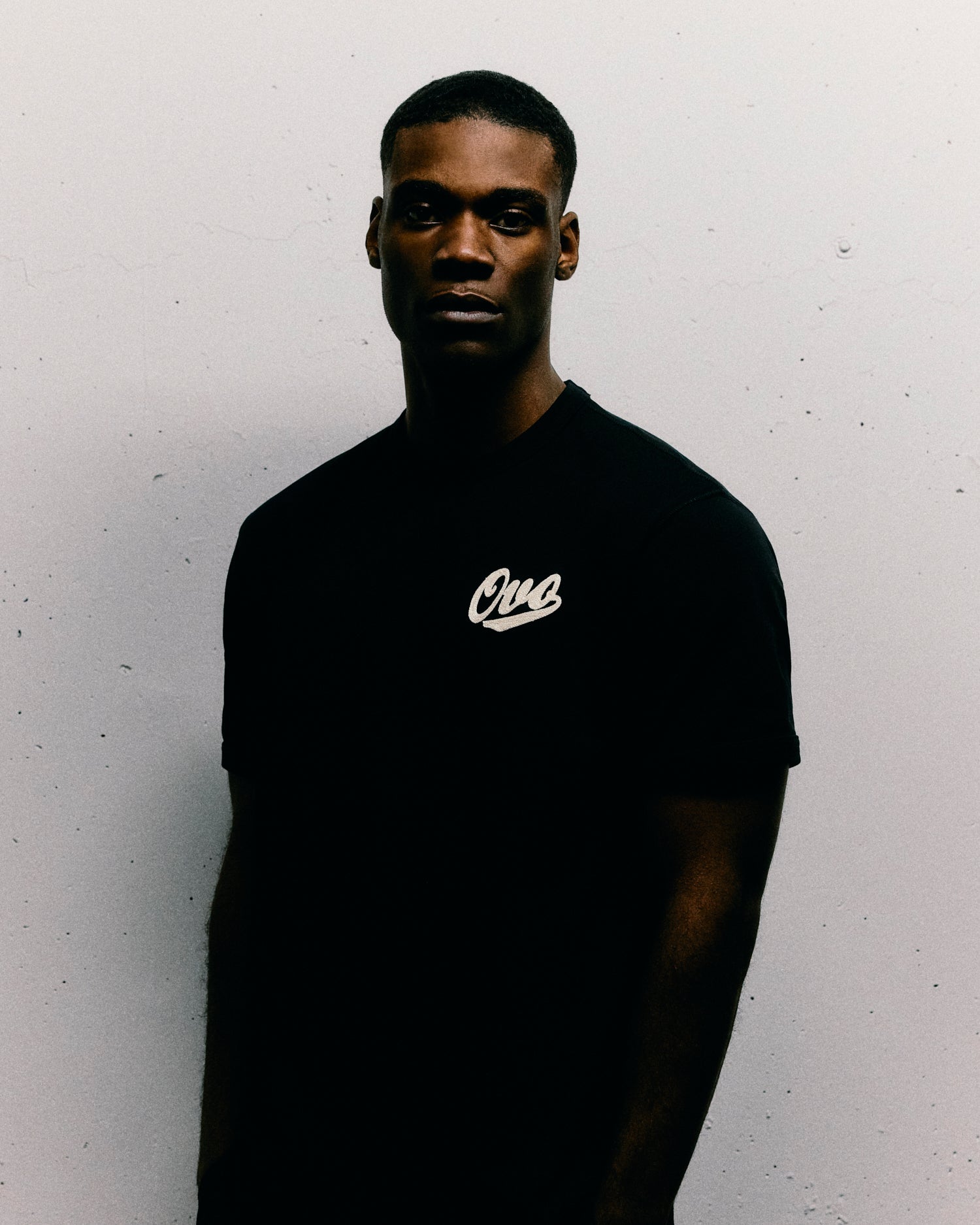 Man wearing a black October's Very Own t-shirt with a logo on a white background
