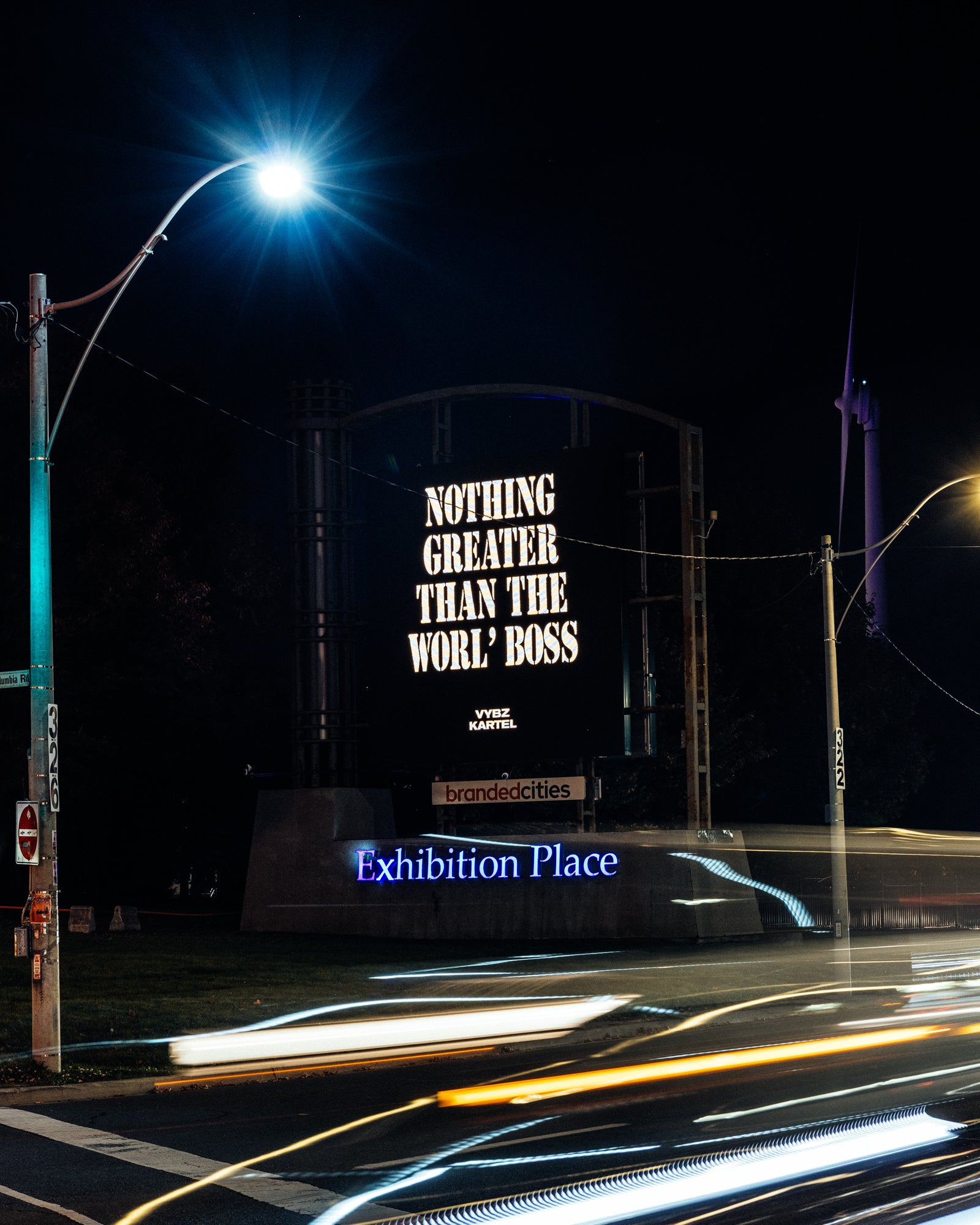 Billboard with motivational quote 'Nothing Greater Than The Worl Boss' at night, illuminated by streetlights.