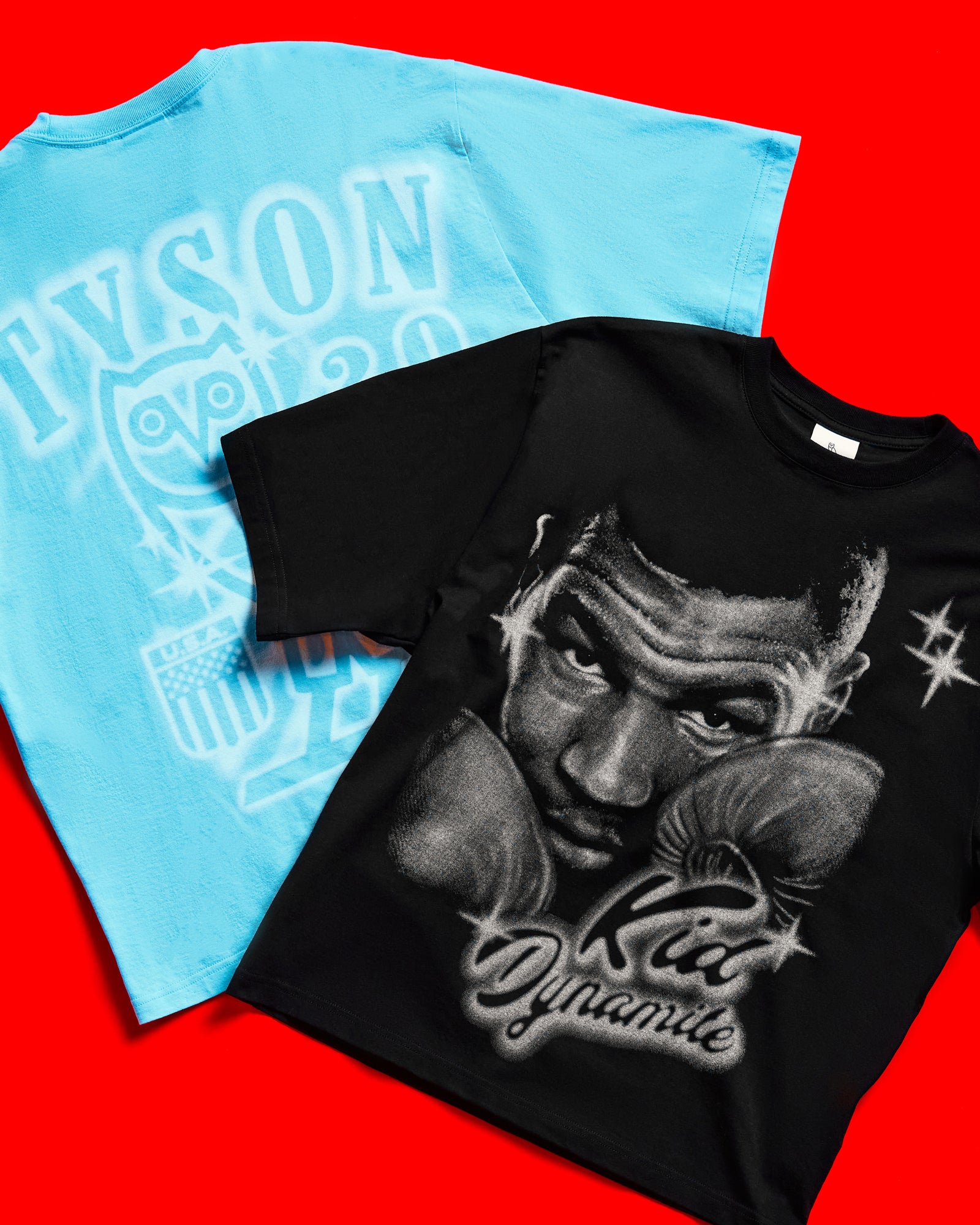 Two October's Very Own x Tyson t-shirts, one blue and one black with a graphic design, on a red background.