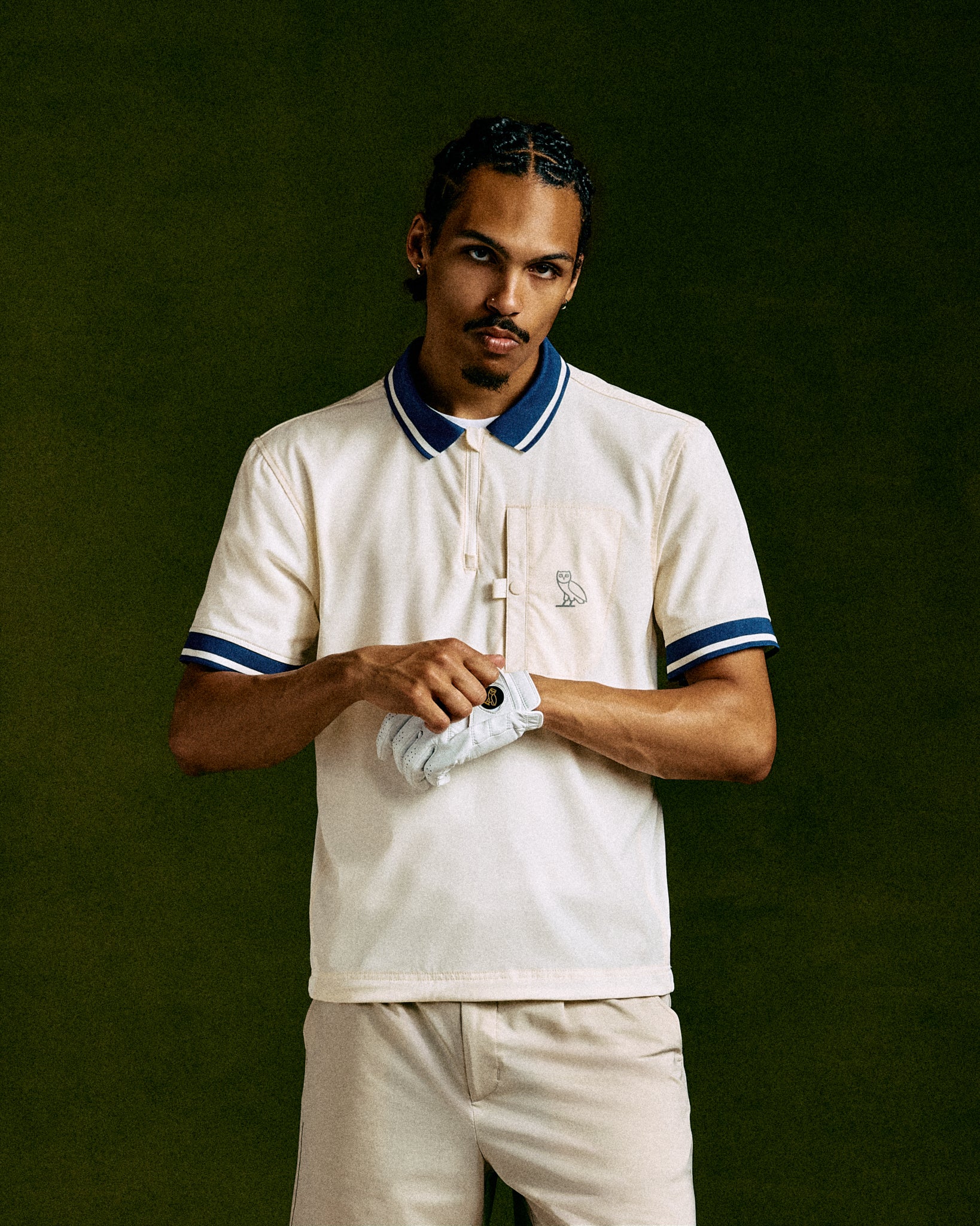 Cream polo shirt with navy and white striped collar and sleeve trim, featuring small chest logo.