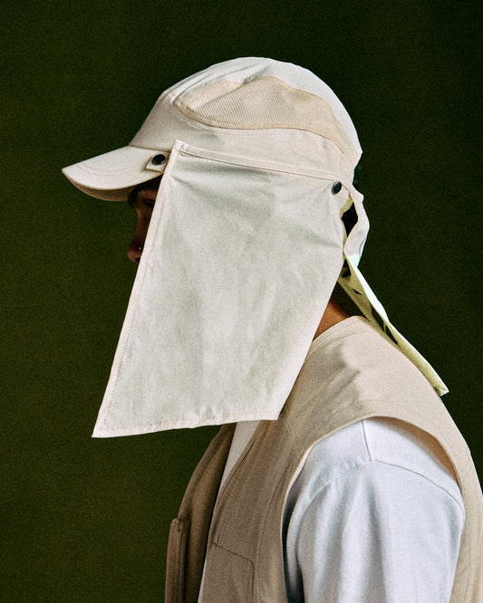 Antique white golf cap with extended neck shield and adjustable chin strap worn by model.