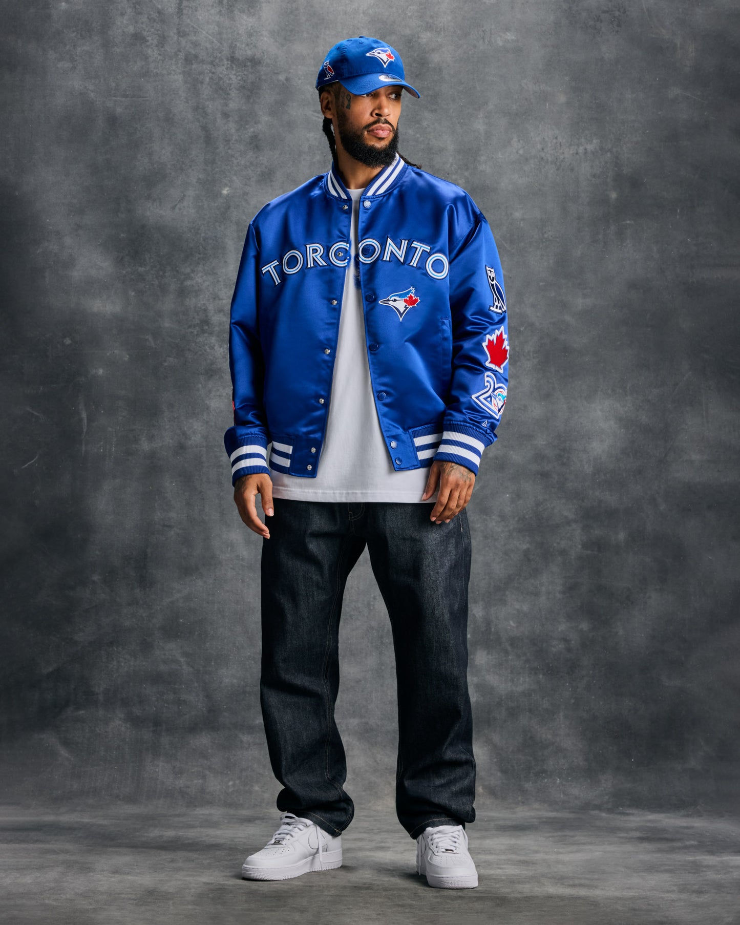 Blue varsity jacket with Toronto Blue Jays logo, "Toronto" text, and white striped ribbing on cuffs and collar.