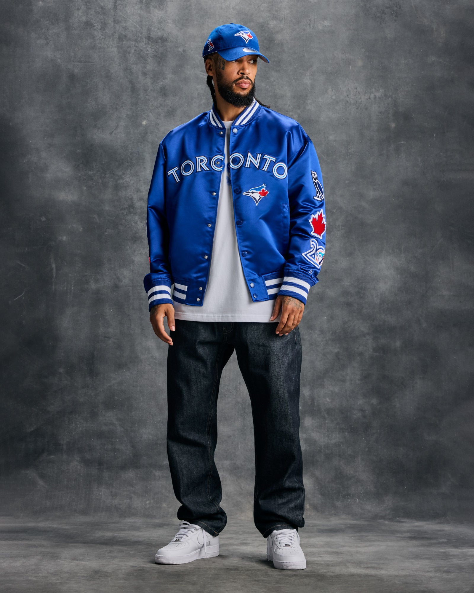 Blue varsity jacket with Toronto Blue Jays logo, "Toronto" text, and white striped ribbing on cuffs and collar.