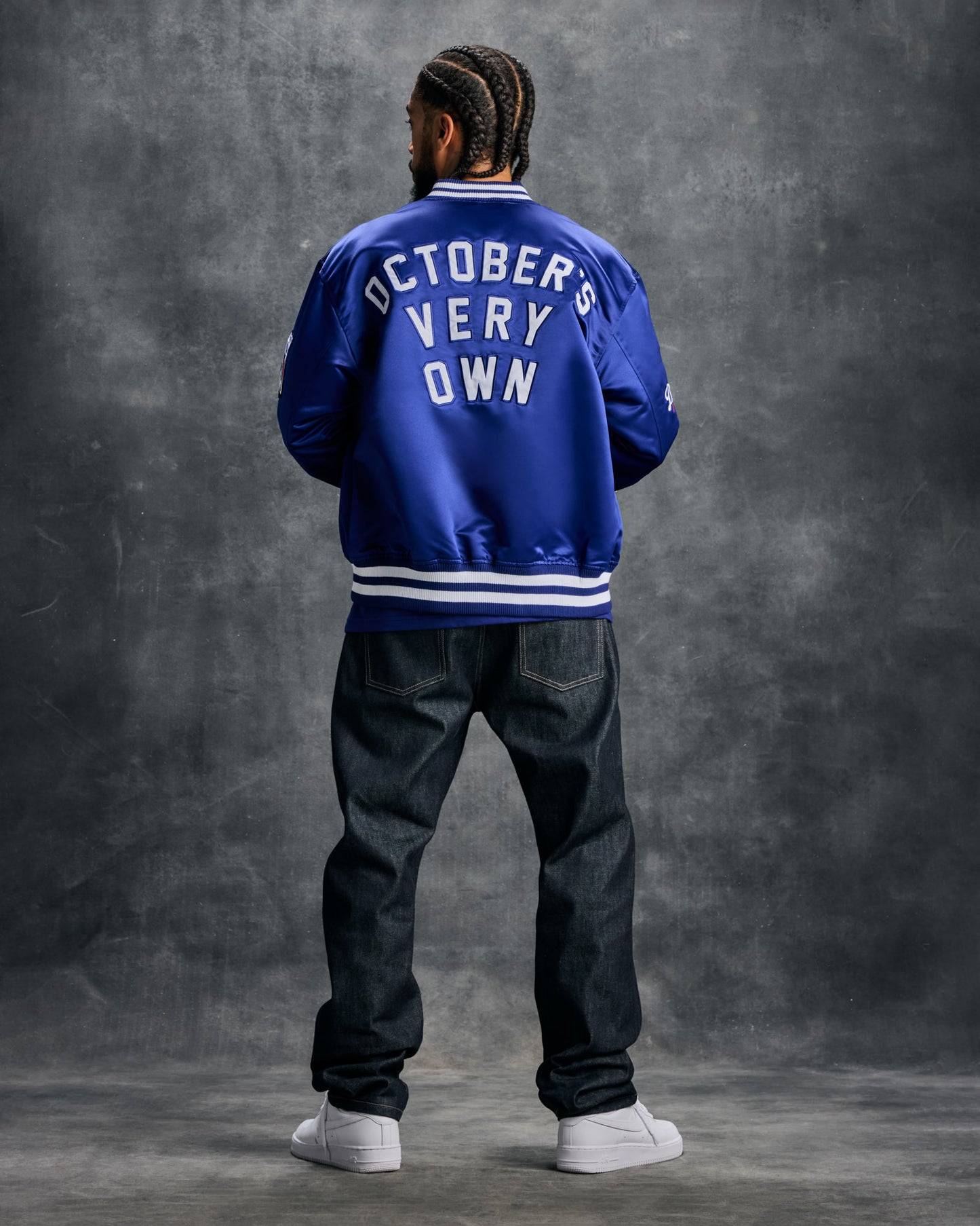 Blue varsity jacket with white "October's Very Own" text on back, white stripe trim at collar and cuffs.