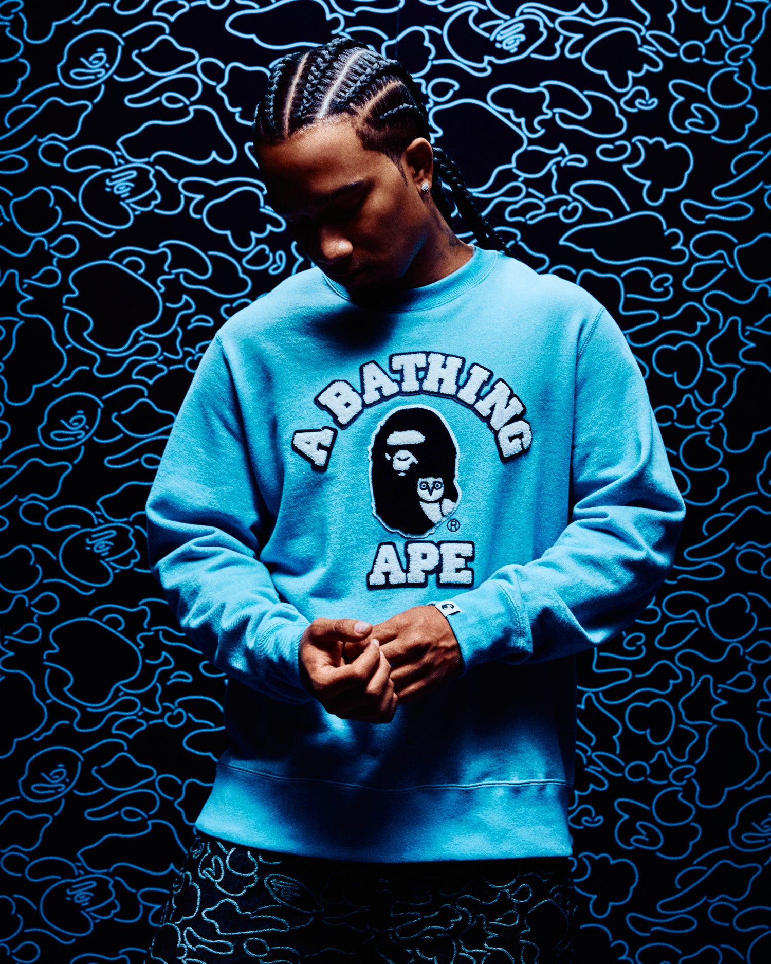 Person wearing a blue 'A Bathing Ape' October's Very Own sweatshirt against a dark background with blue patterns.