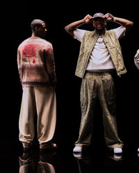 Translation missing: fr.Two individuals standing against a black background, one with a rose design on their sweater