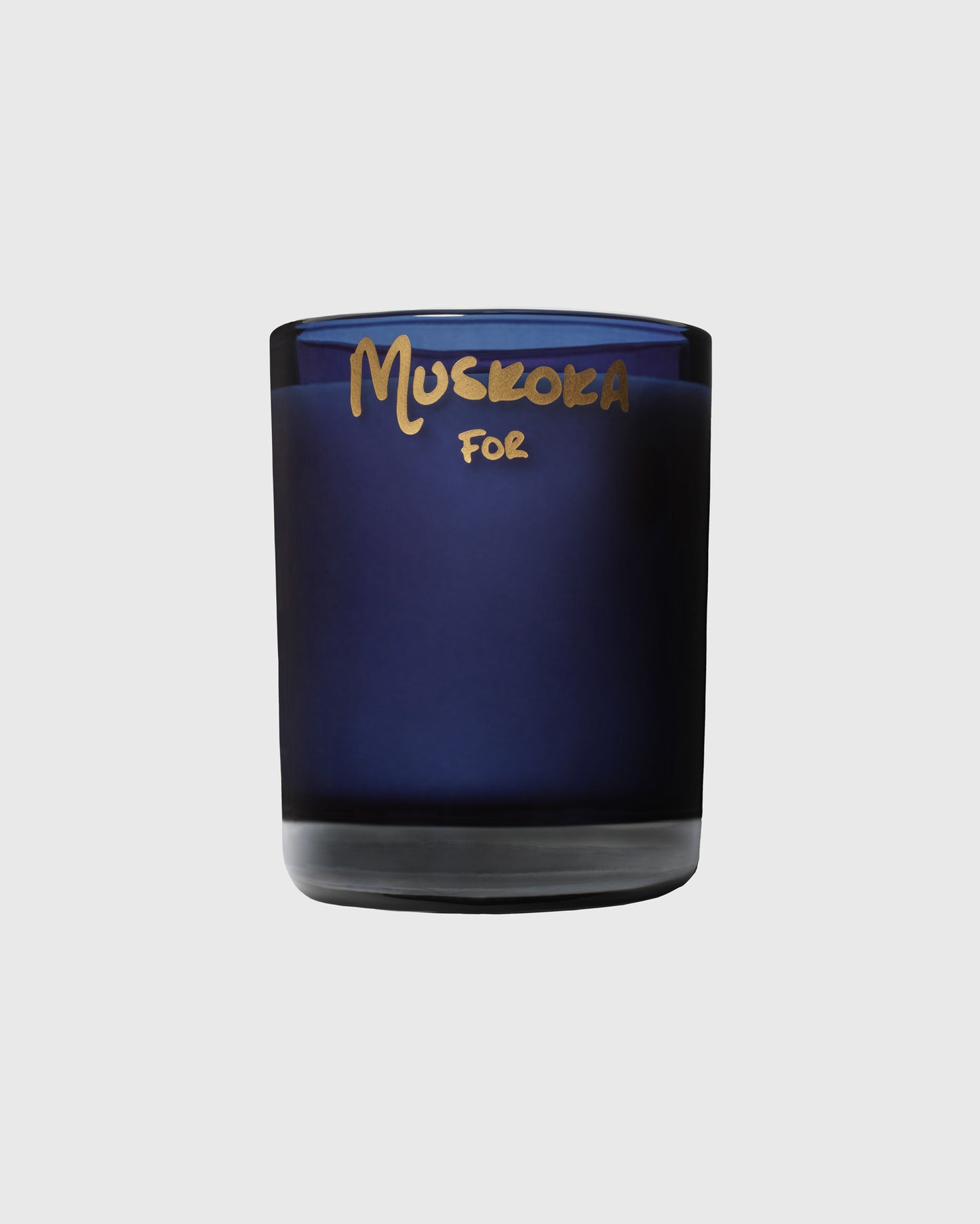 Dark blue glass candle with gold "Muskoka For" text on the label.