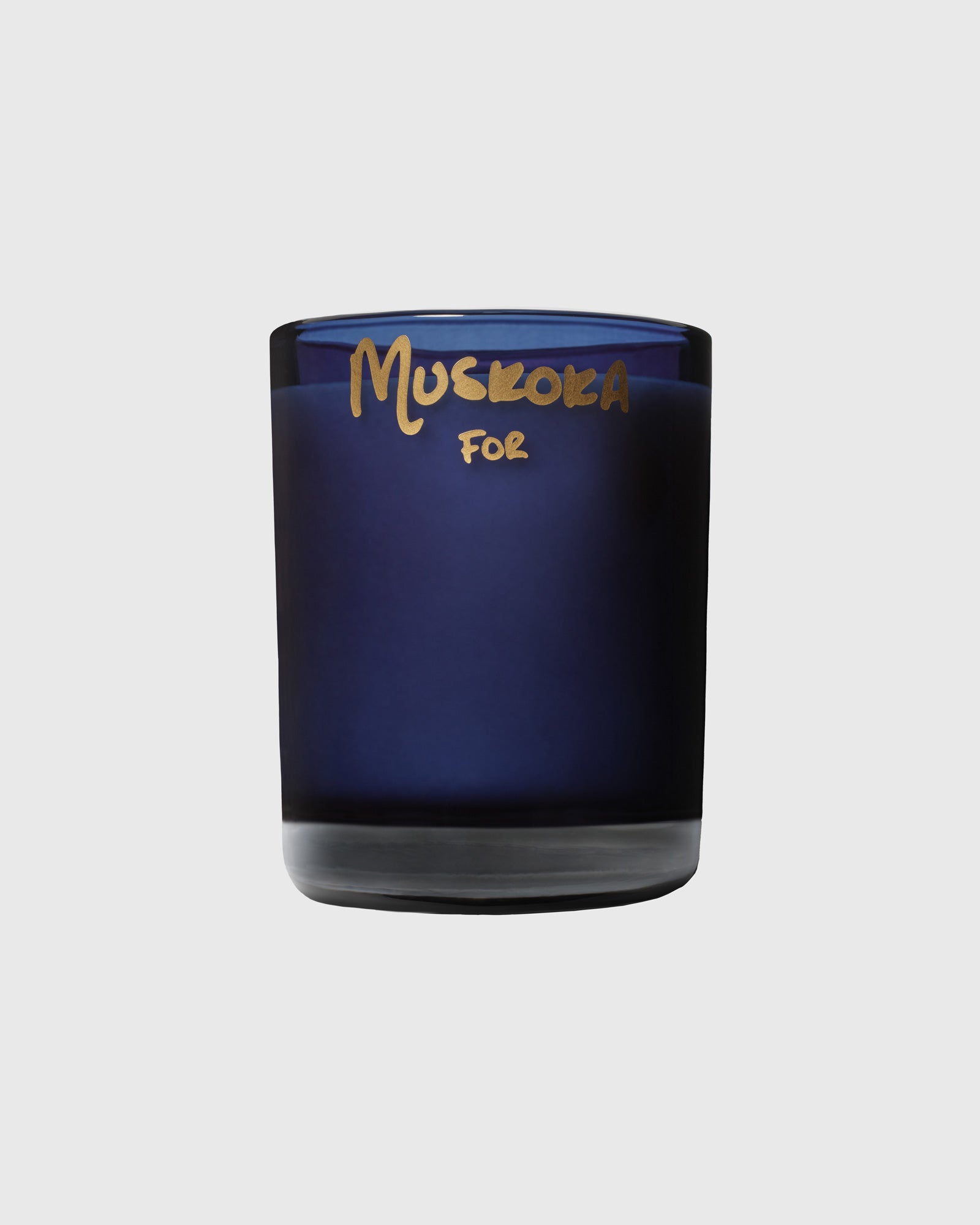 Dark blue glass candle with gold "Muskoka For" text on the label.