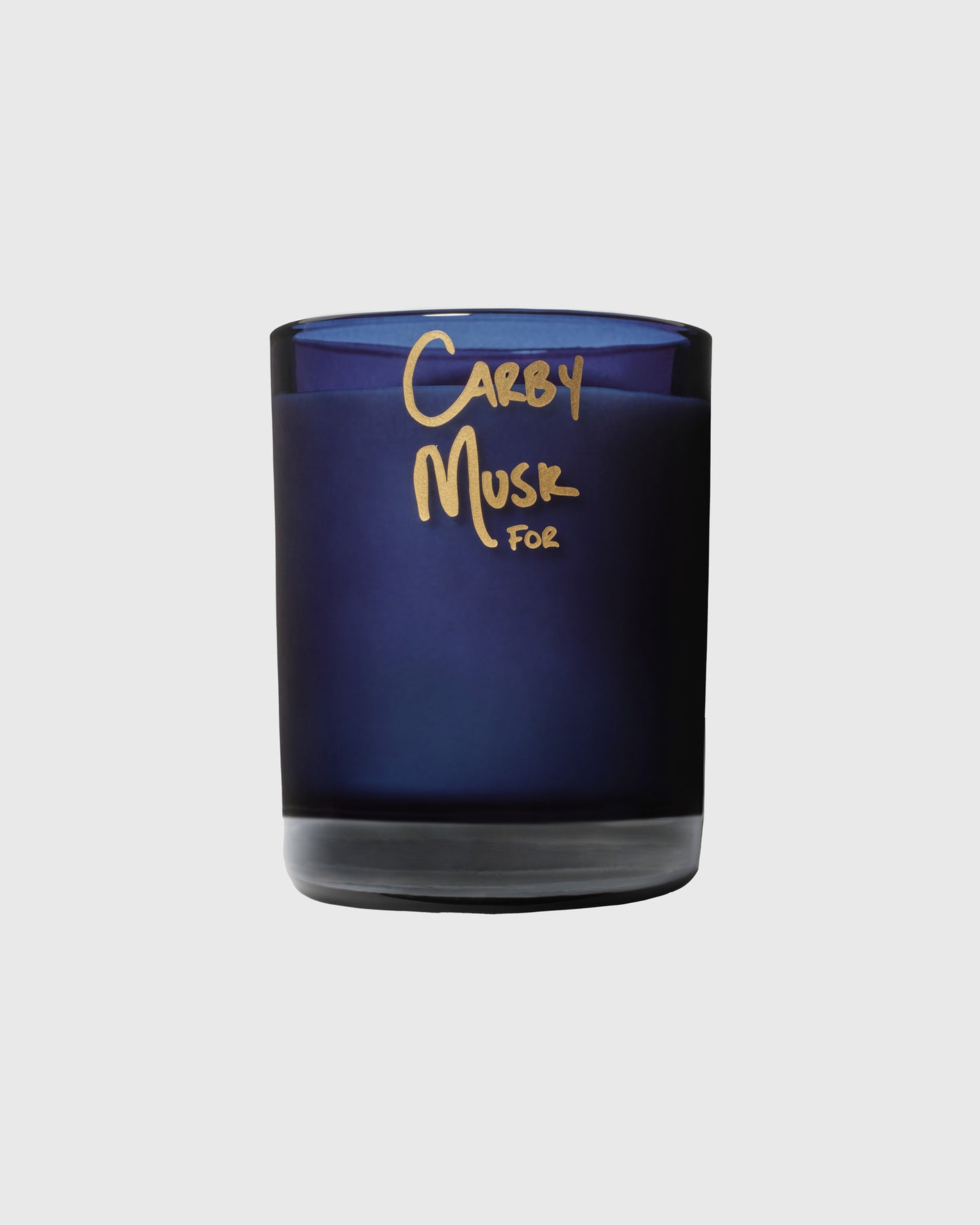 Dark blue glass candle jar with gold "Carby Musk For" text on front label.