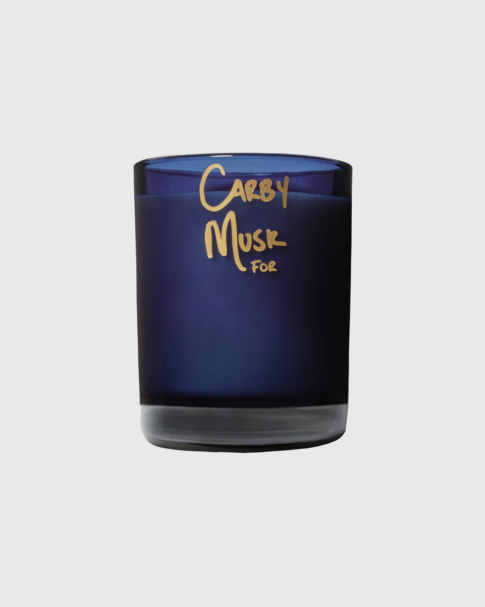 Dark blue glass candle jar with gold "Carby Musk For" text on front label.