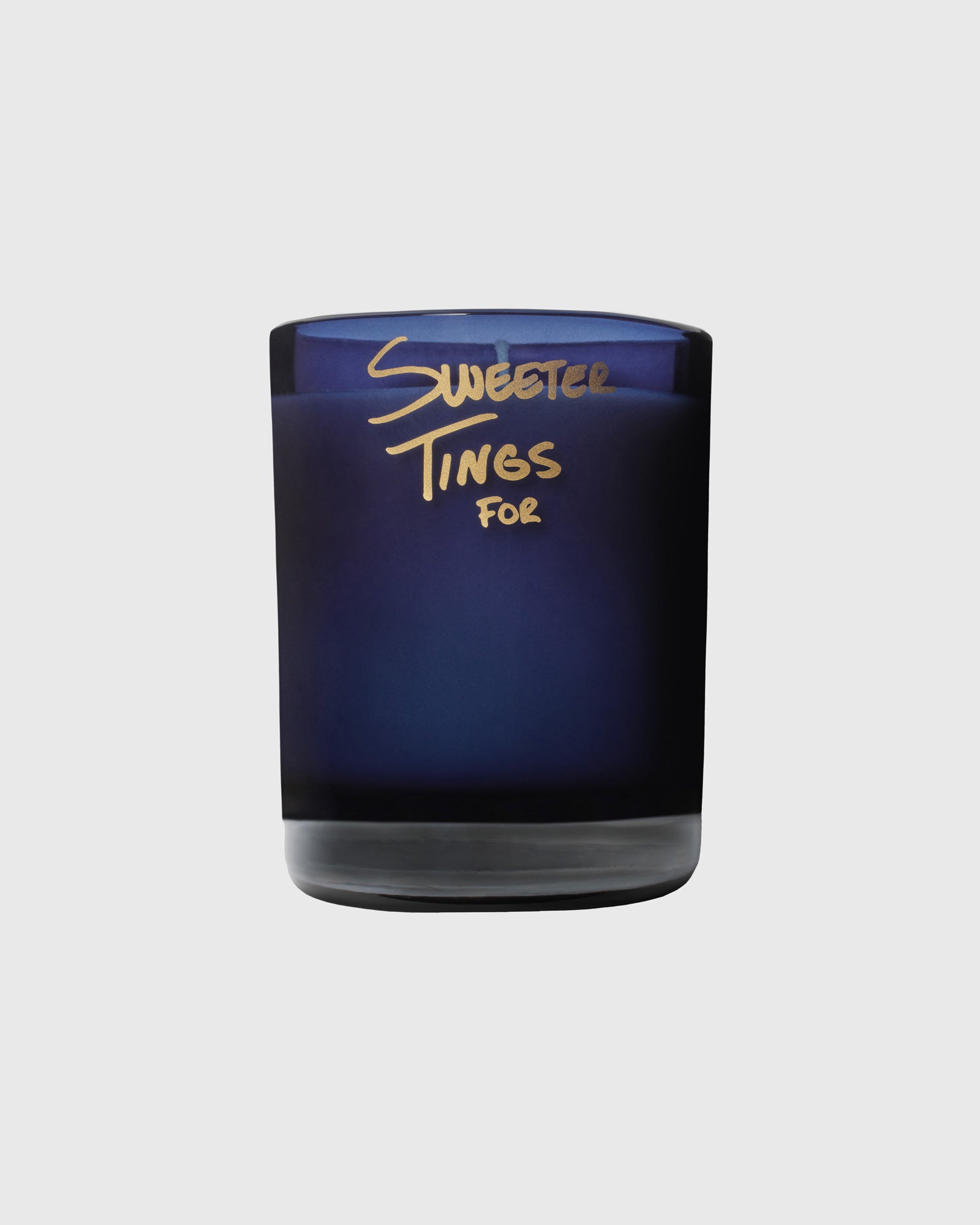 Navy glass candle with gold "Sweeter Tings For" text on label.