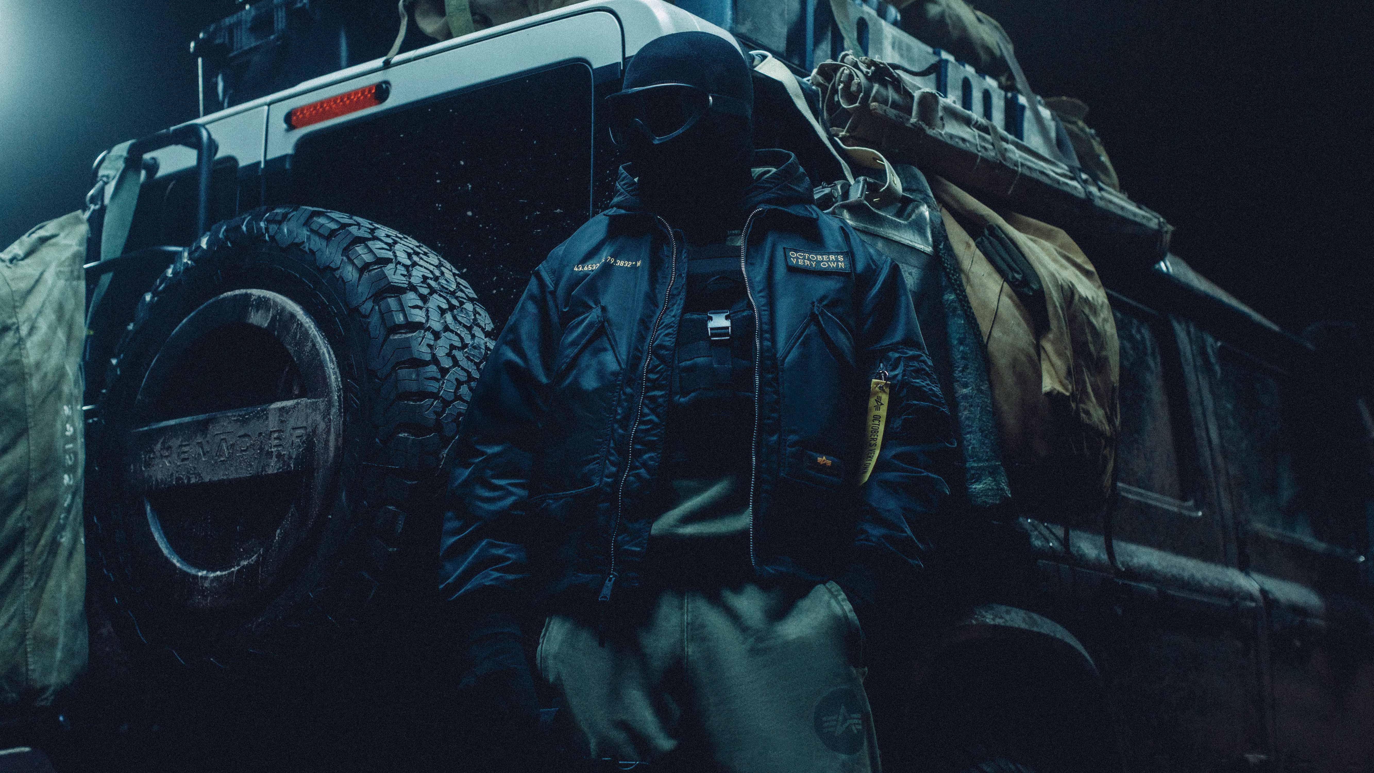 Person leaning on car wearing October's Very Own x Alpha Industries