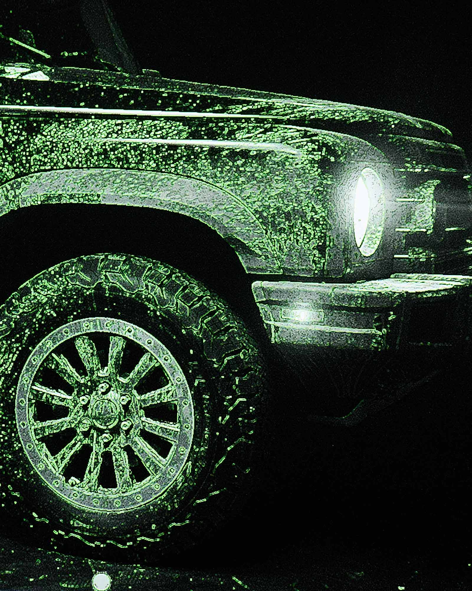 Close-up of a vehicle's front wheel and headlight with a greenish tint on a dark background