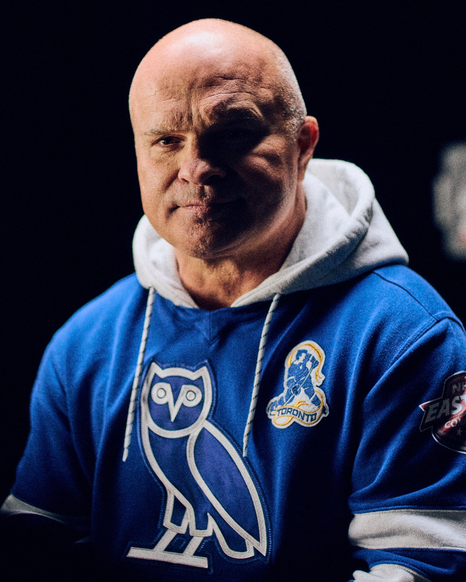 Tie Domi wearing a blue October's Very Own x NHL hoodie with a logo on a black background