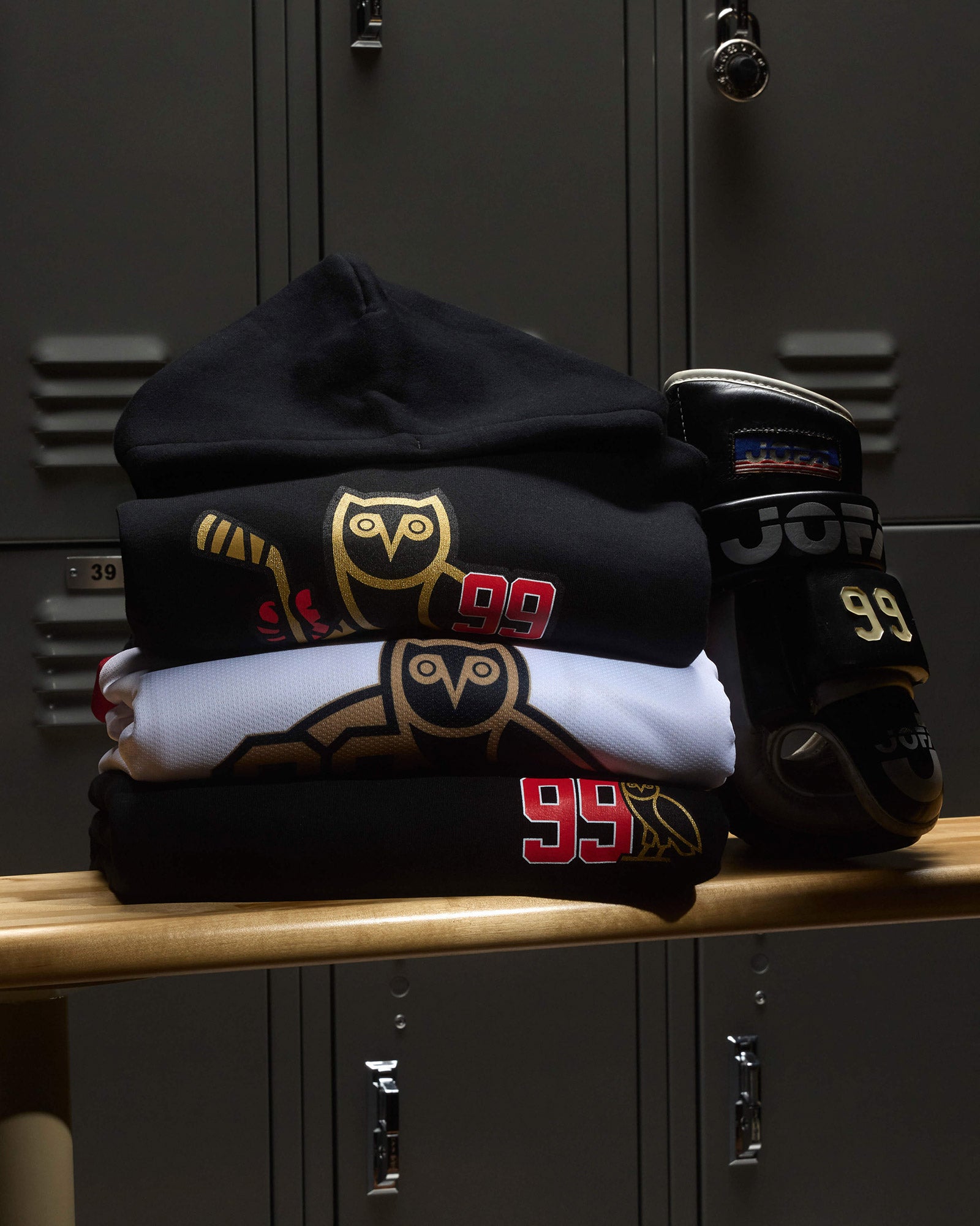 Stack of Ocrober's Very Own hoodies and socks on a locker shelf with lockers in the background