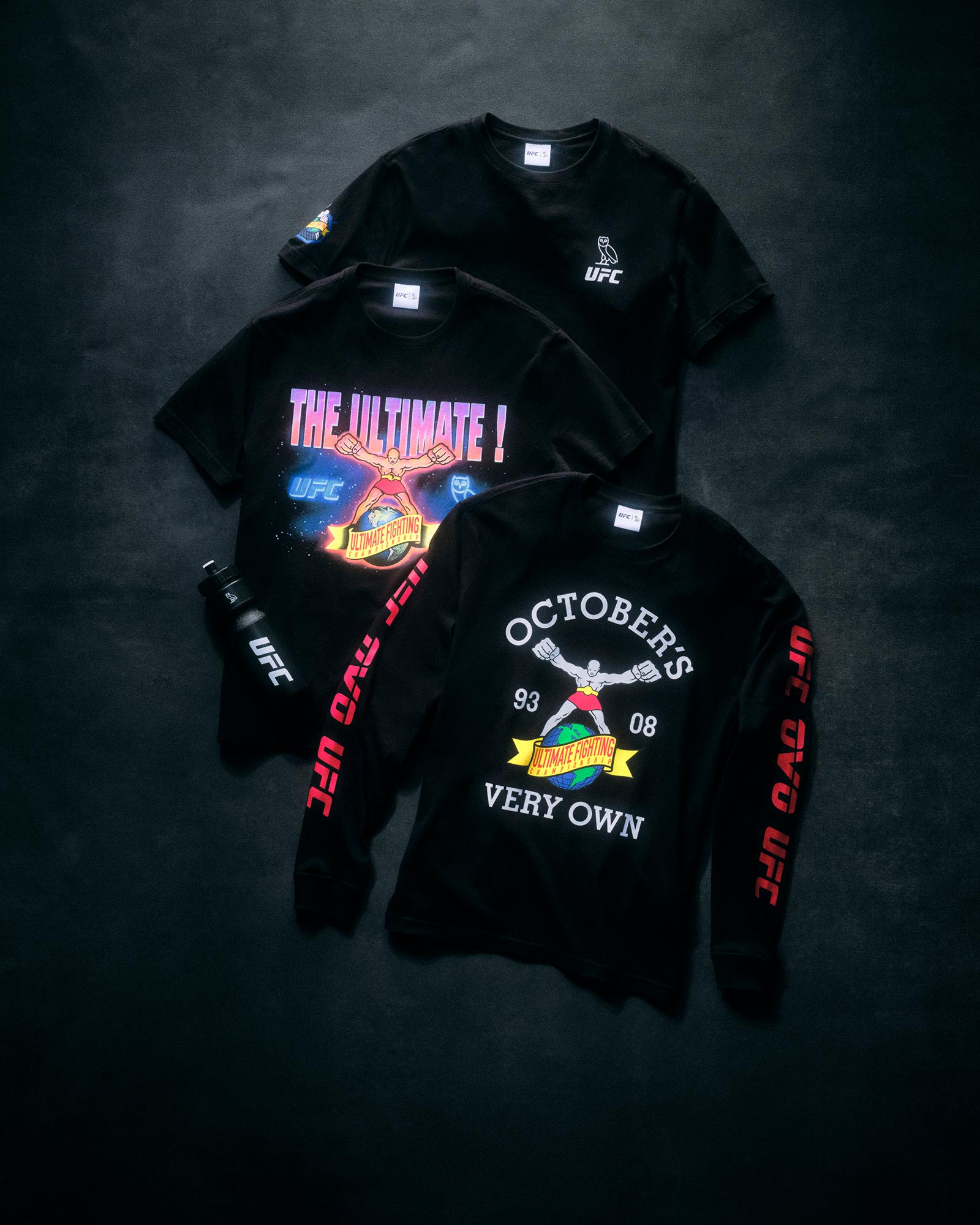 Three October's Very Own x UFC black t-shirts with UFC branding and graphics on a dark textured background