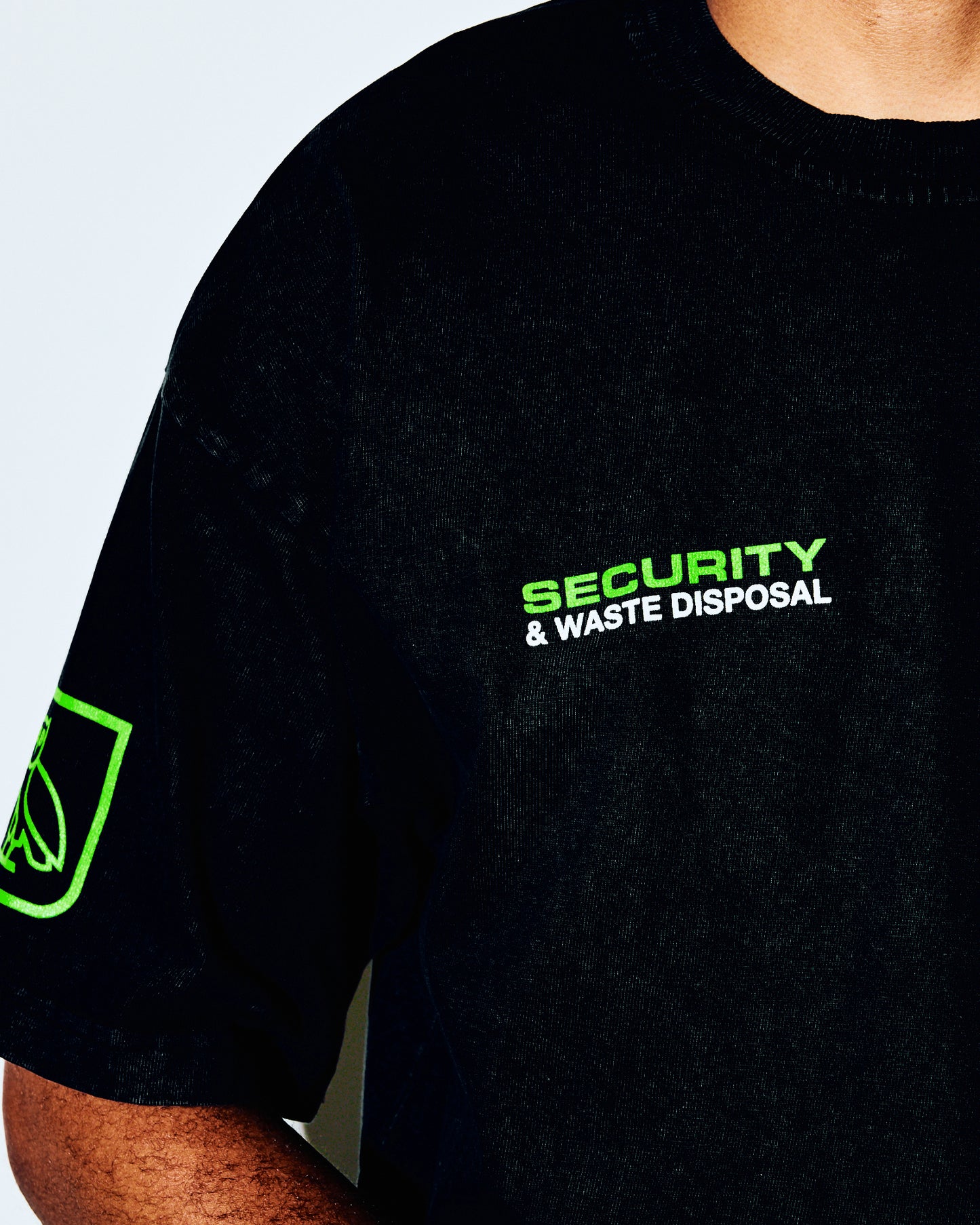 Black t-shirt with neon green "Security & Waste Disposal" text on chest and sleeve graphic.