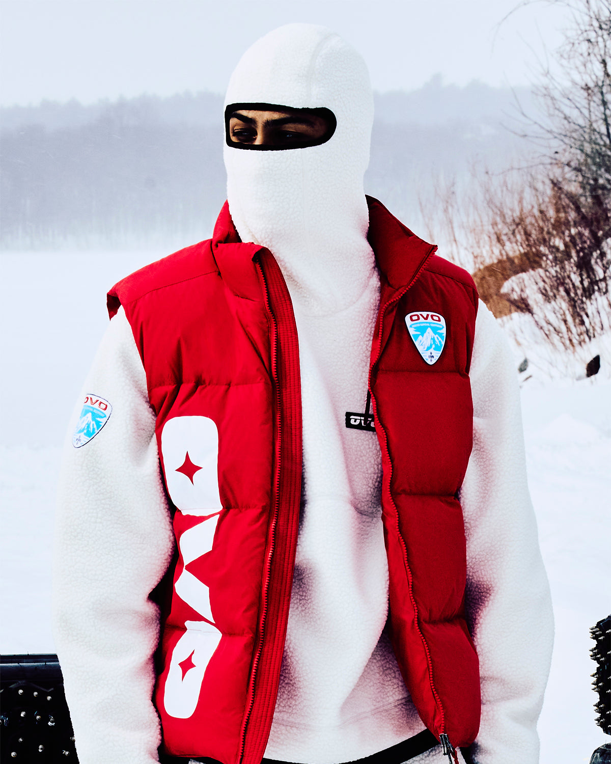 Person wearing a red OVO vest and white helmet in a snowy landscape