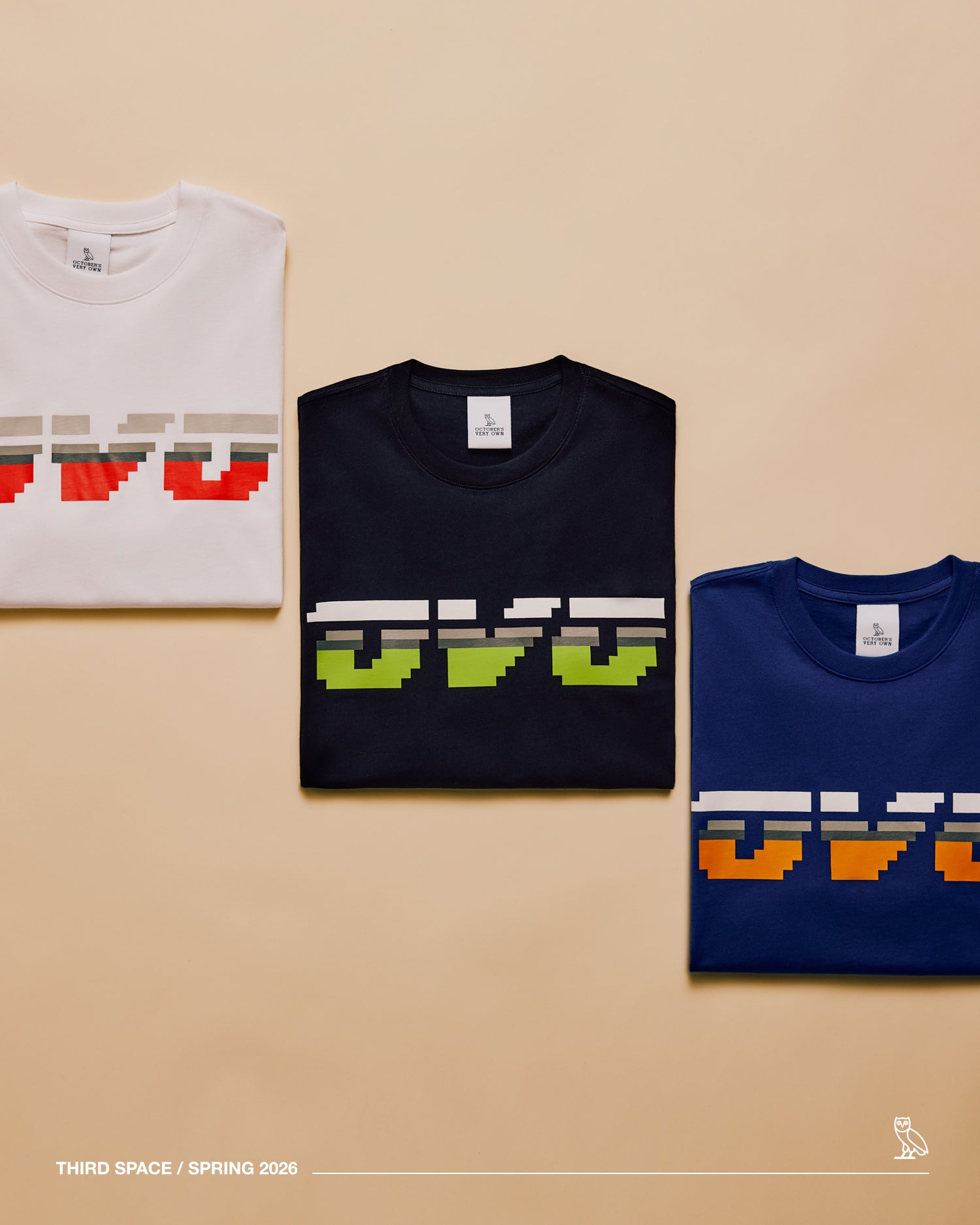 Three folded t-shirts with pixelated October'd Very Own logo design on a beige background