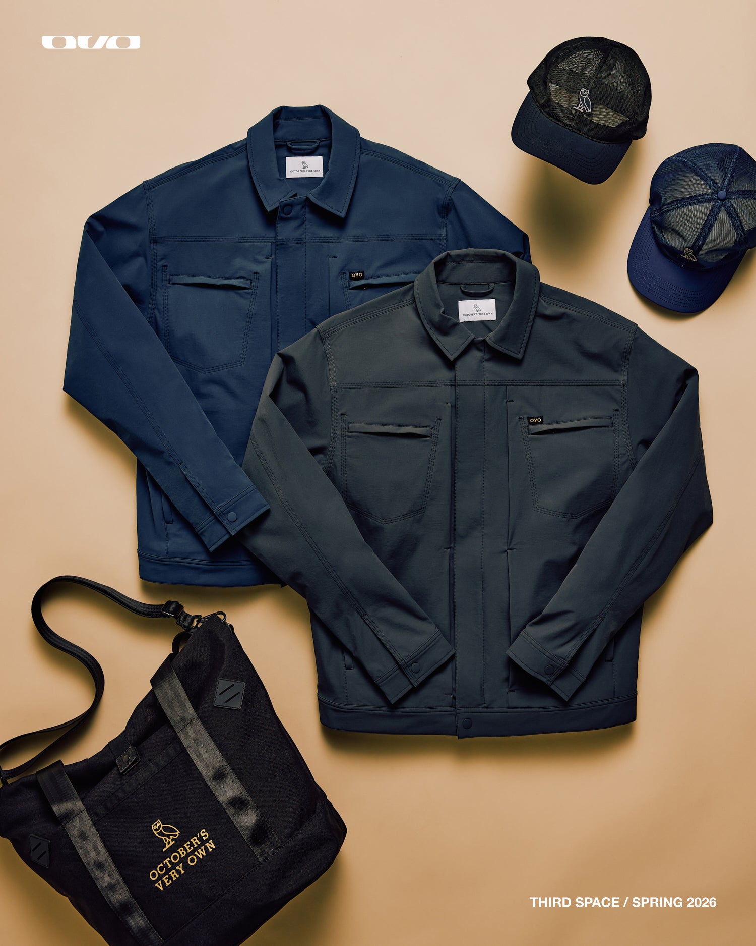 Two navy jackets, two caps, and a black bag on a beige background with October's Very Own branding.