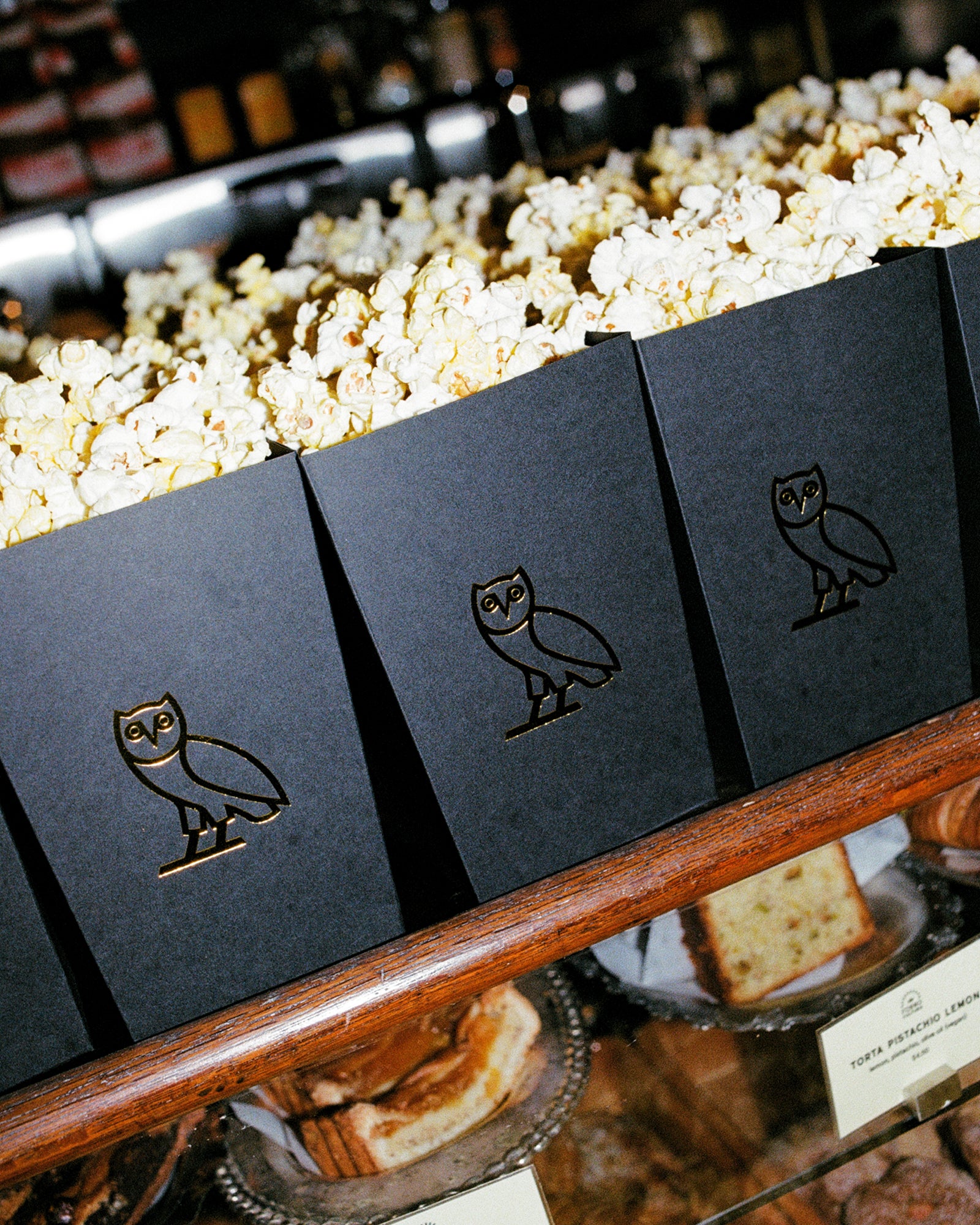 Black boxes with the October's Very Own logo on a wooden shelf with popcorn in the background