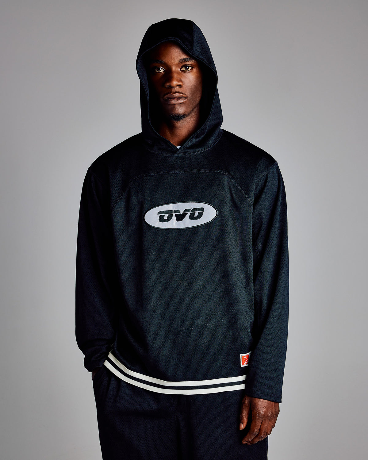 Black mesh basketball hoodie with white oval logo on chest and white stripe trim at hem.