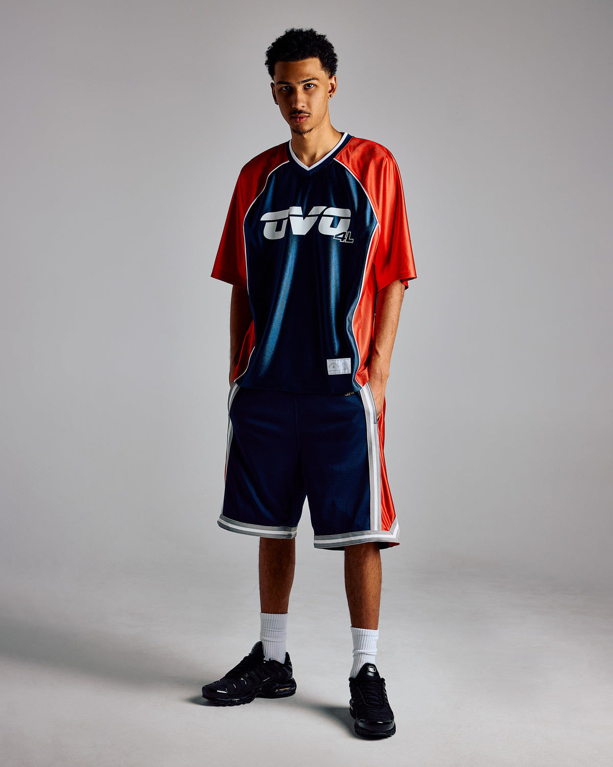 Man wearing navy basketball shorts with red and white side stripes and white trim at hem.