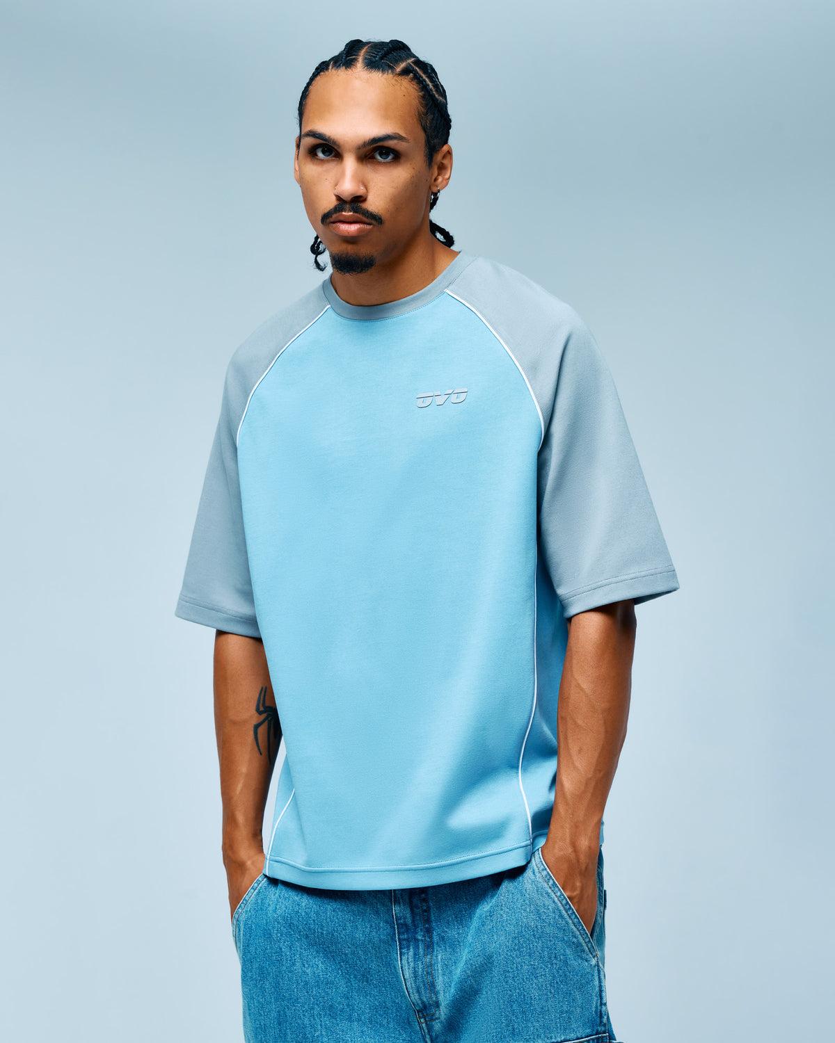 Man wearing light blue and gray raglan training tee with short sleeves and small logo on chest.